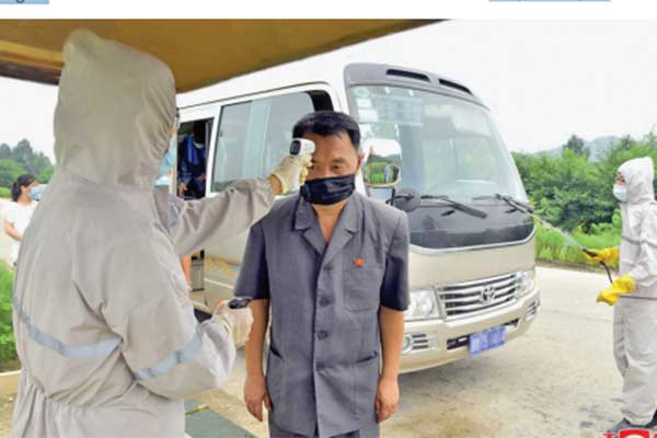 Petugas medis sedang  memeriksa suhu tubuh seseorang di Pyongyang