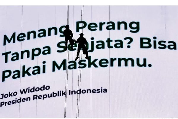 Pekerja membersihkan layar iklan pesan layanan masyarakat mengenai penanganan covid-19 di Jakarta, kemarin.