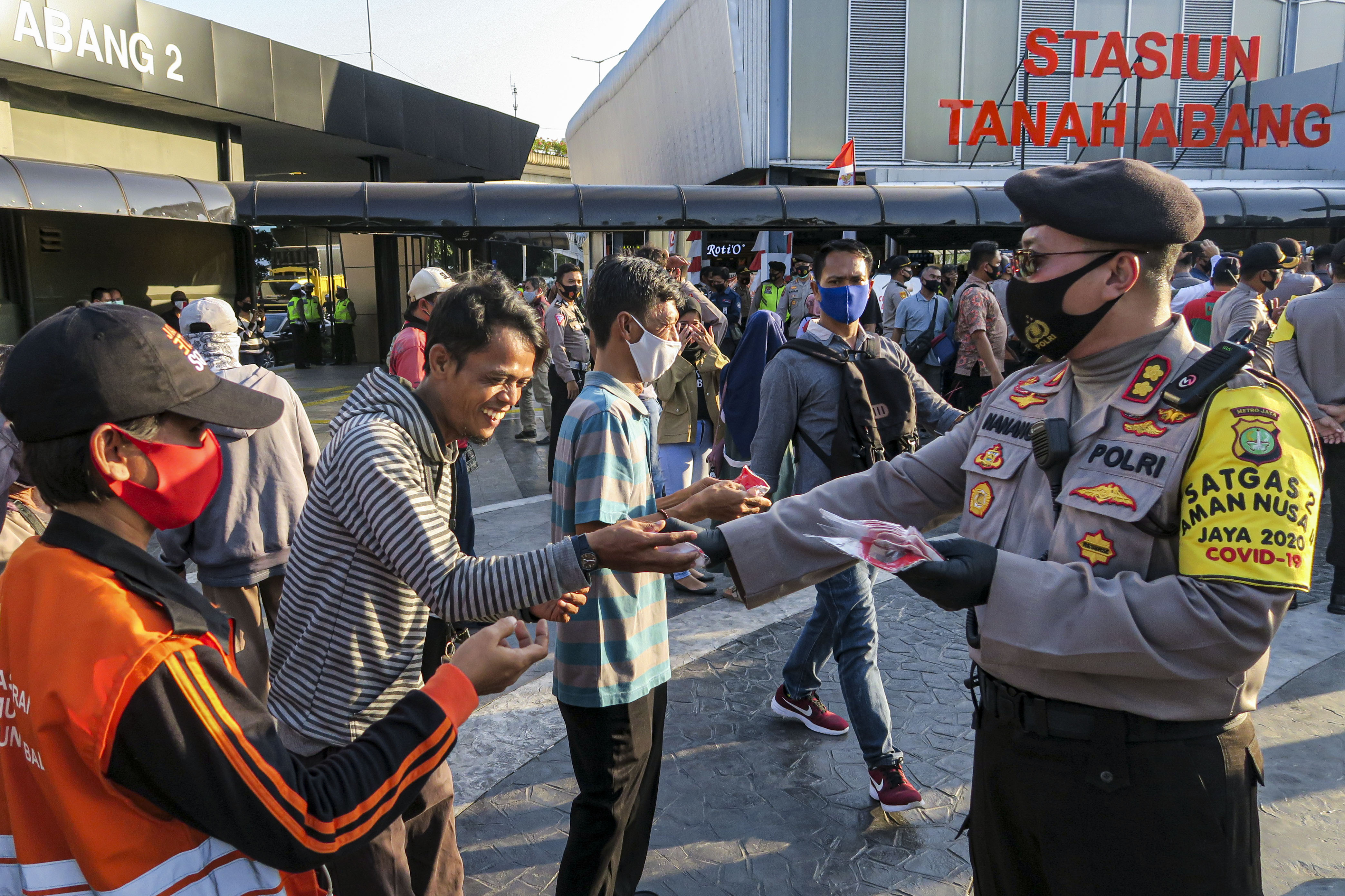 Personel Polri membagikan masker kepada warga di Stasiun Tanah Abang, Jakarta.