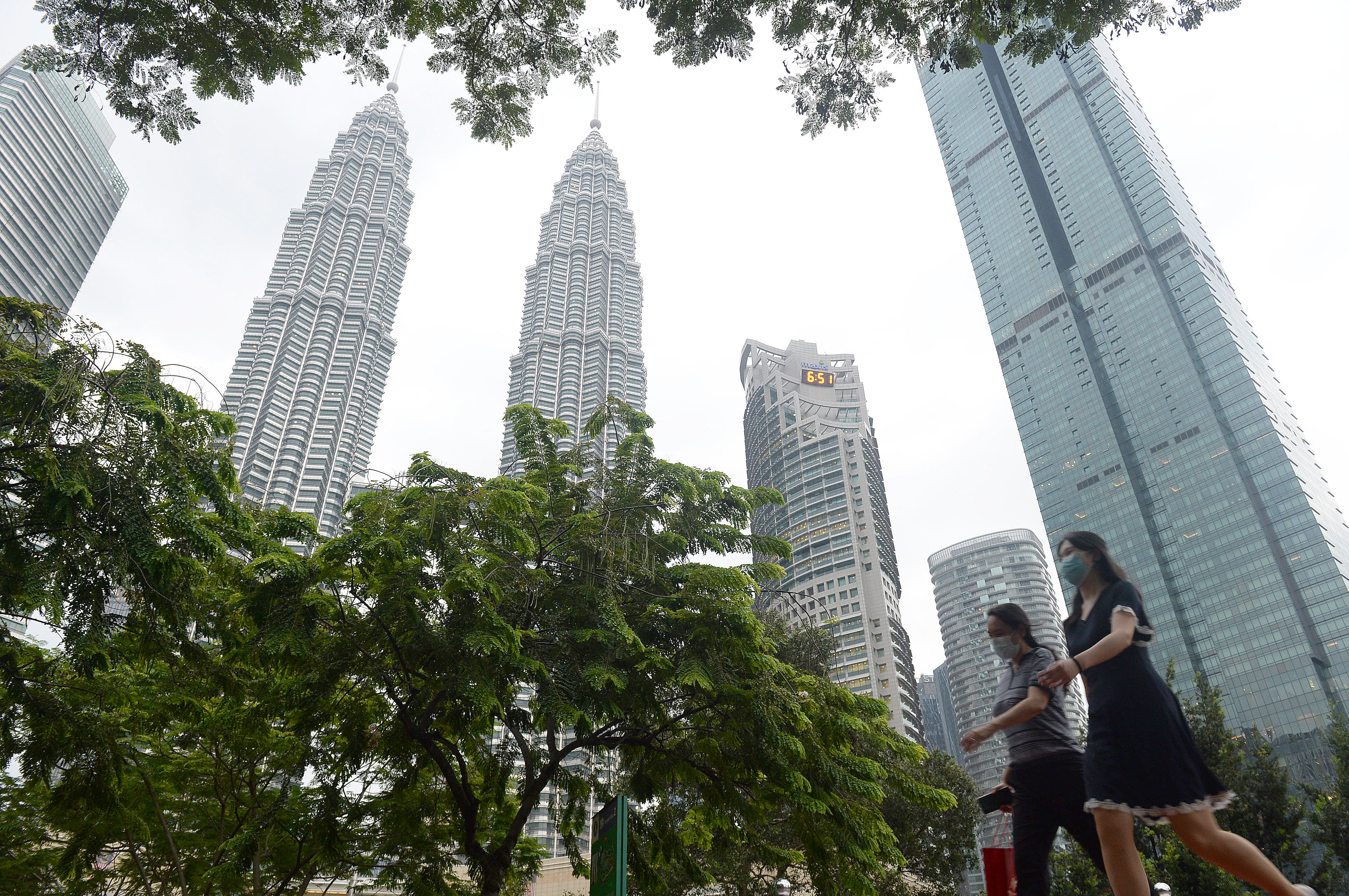 Warga berjalan di kawasan Menara Berkembar Petronas Kuala Lumpur memakai masker (7/9/2020)