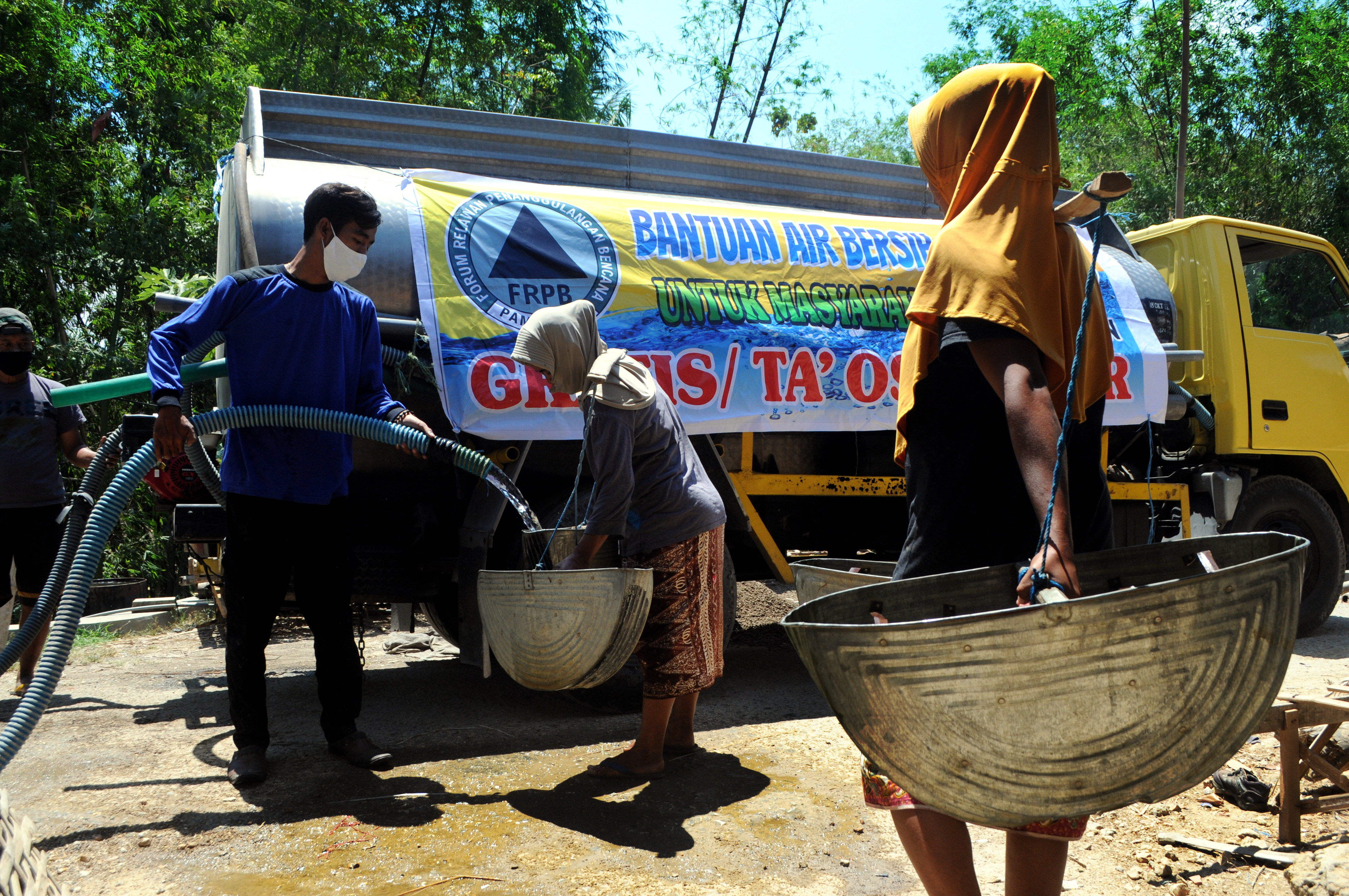 Relawan memasukkan air ke dalam timba saat pendistribusian air bersih di Desa Pamoroh, Pamekasan, Jawa Timur, kemarin.