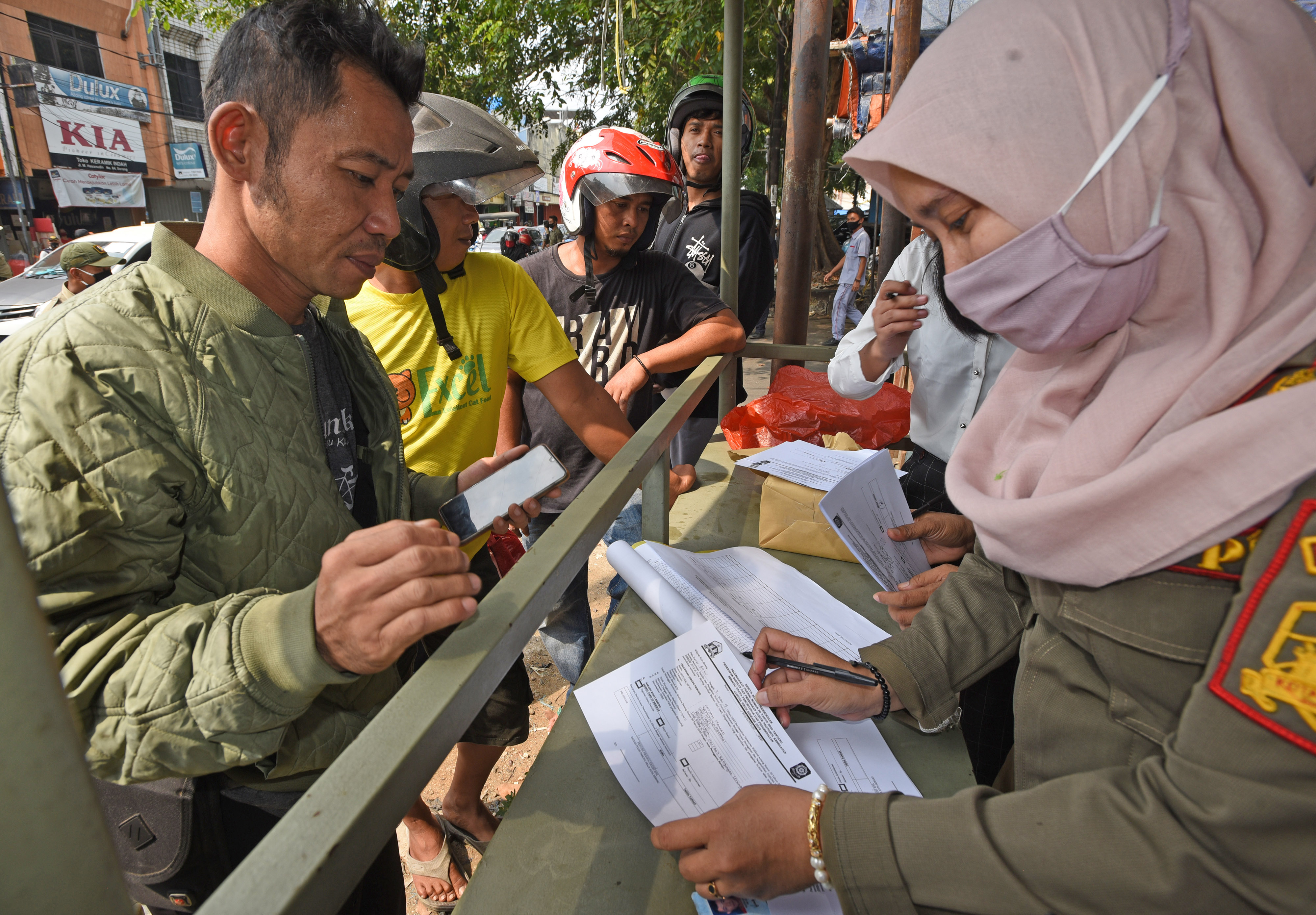 Anggota Satpol PP mendata warga yang tidak menggunakan masker di tempat umum saat Operasi Penegakkan Disiplin Protokol Kesehatan.