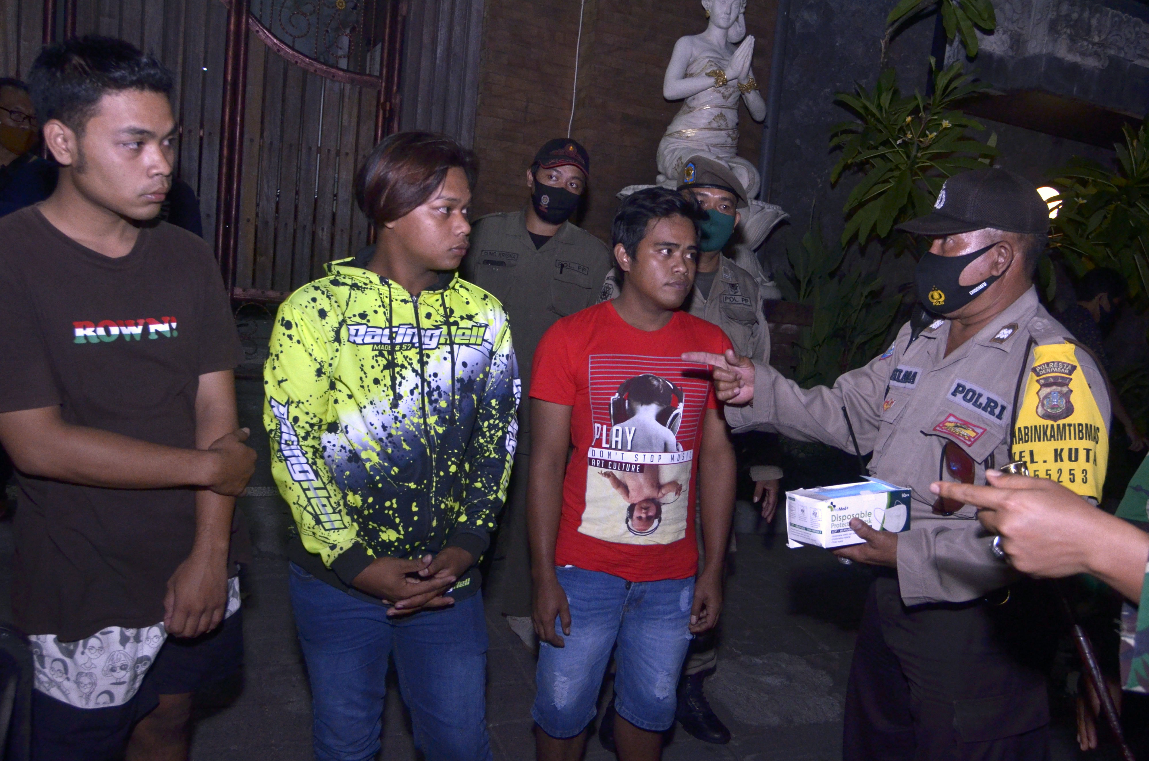 Petugas menegur warga yang tidak mengenakan masker saat melakukan pengawasan prokes di kawasan Kuta, Badung, Bali.