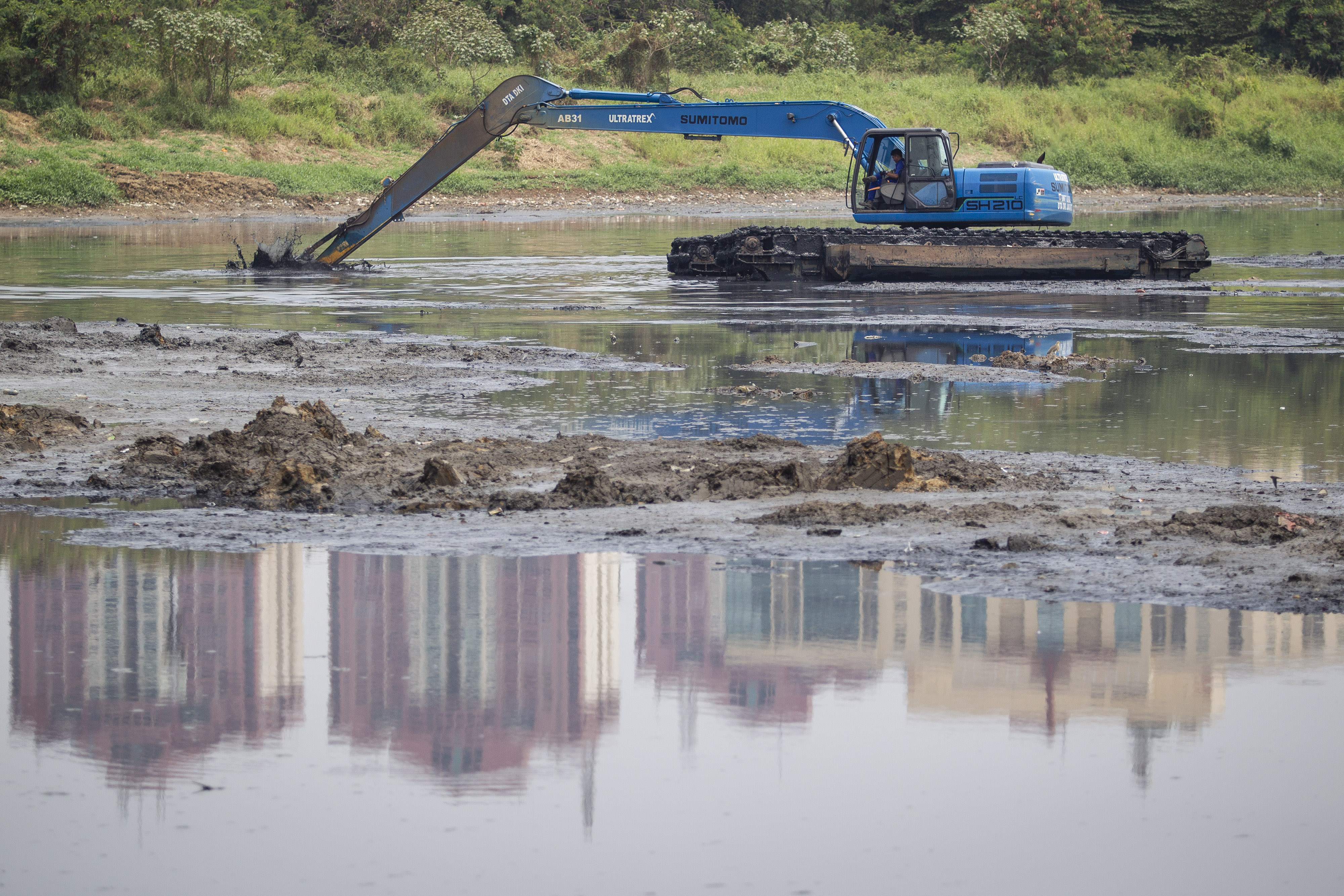 Petugas Dinas Sumber Daya Air (SDA) DKI Jakarta mengoperasikan alat berat untuk mengeruk endapan lumpur di Waduk Ria Rio, Jakarta Timur.