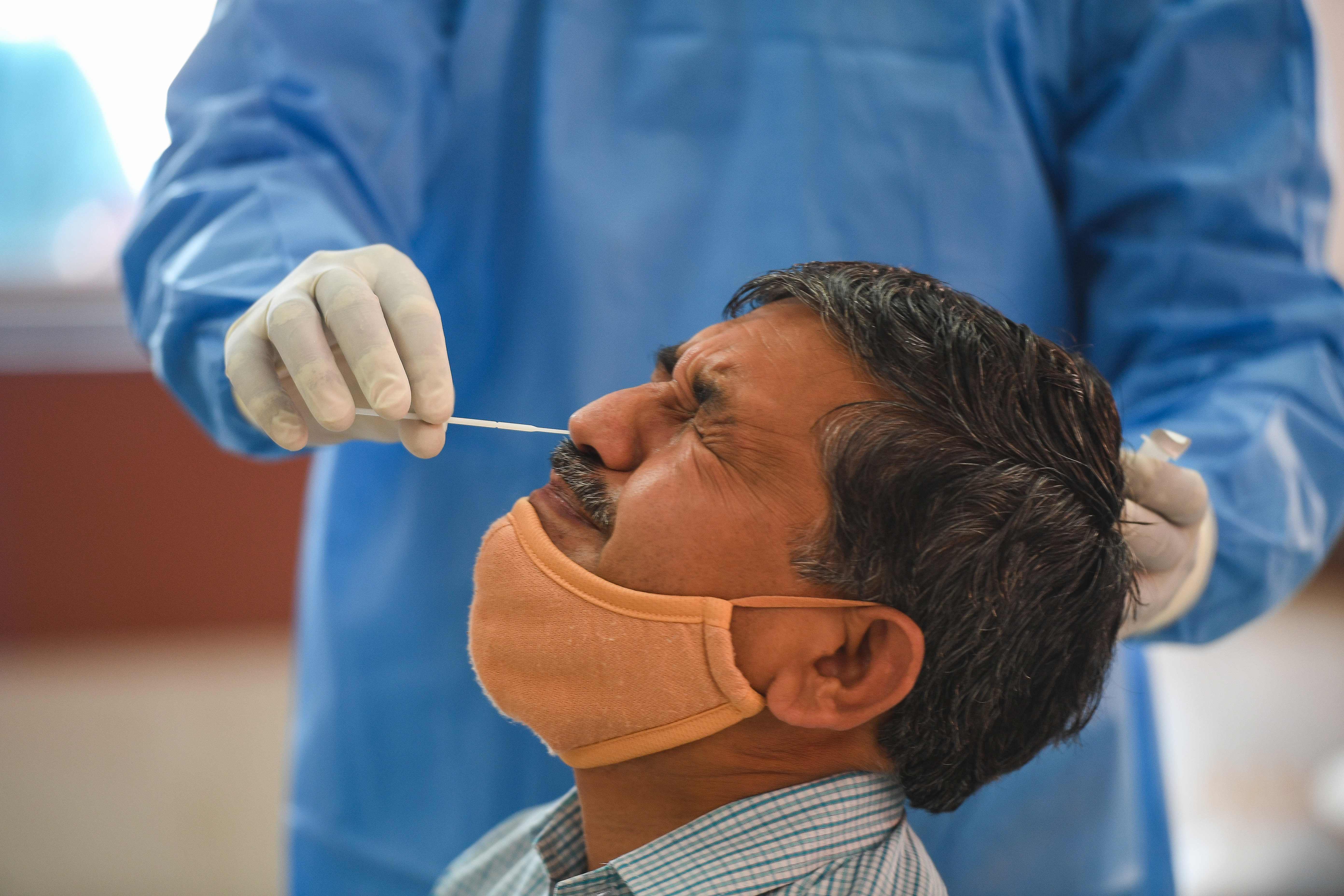 Seorang petugas melakukan swab test di New Delhi, India.