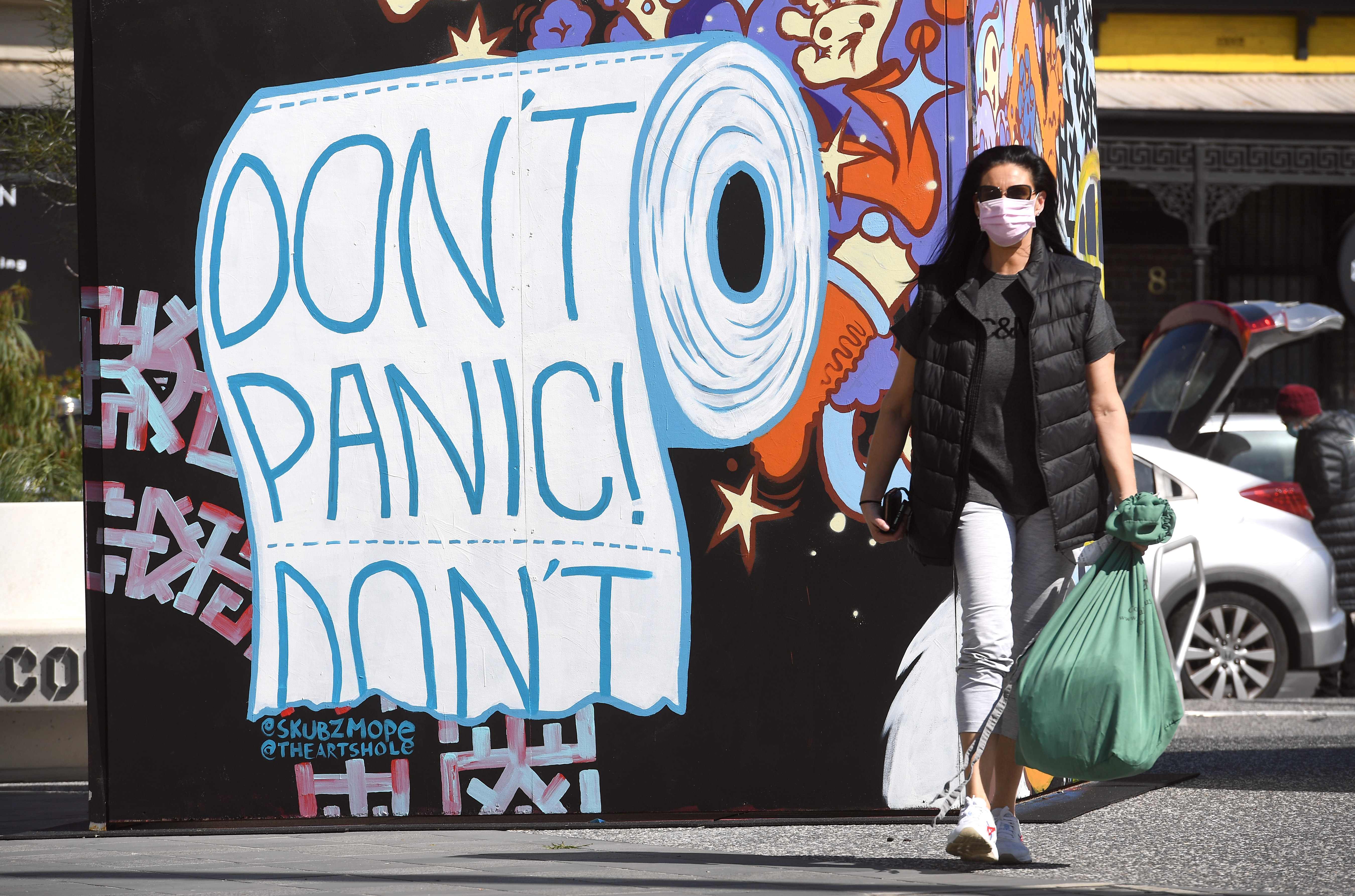 Wanita berjalan melewati mural di Melbourne pada 10 September 2020