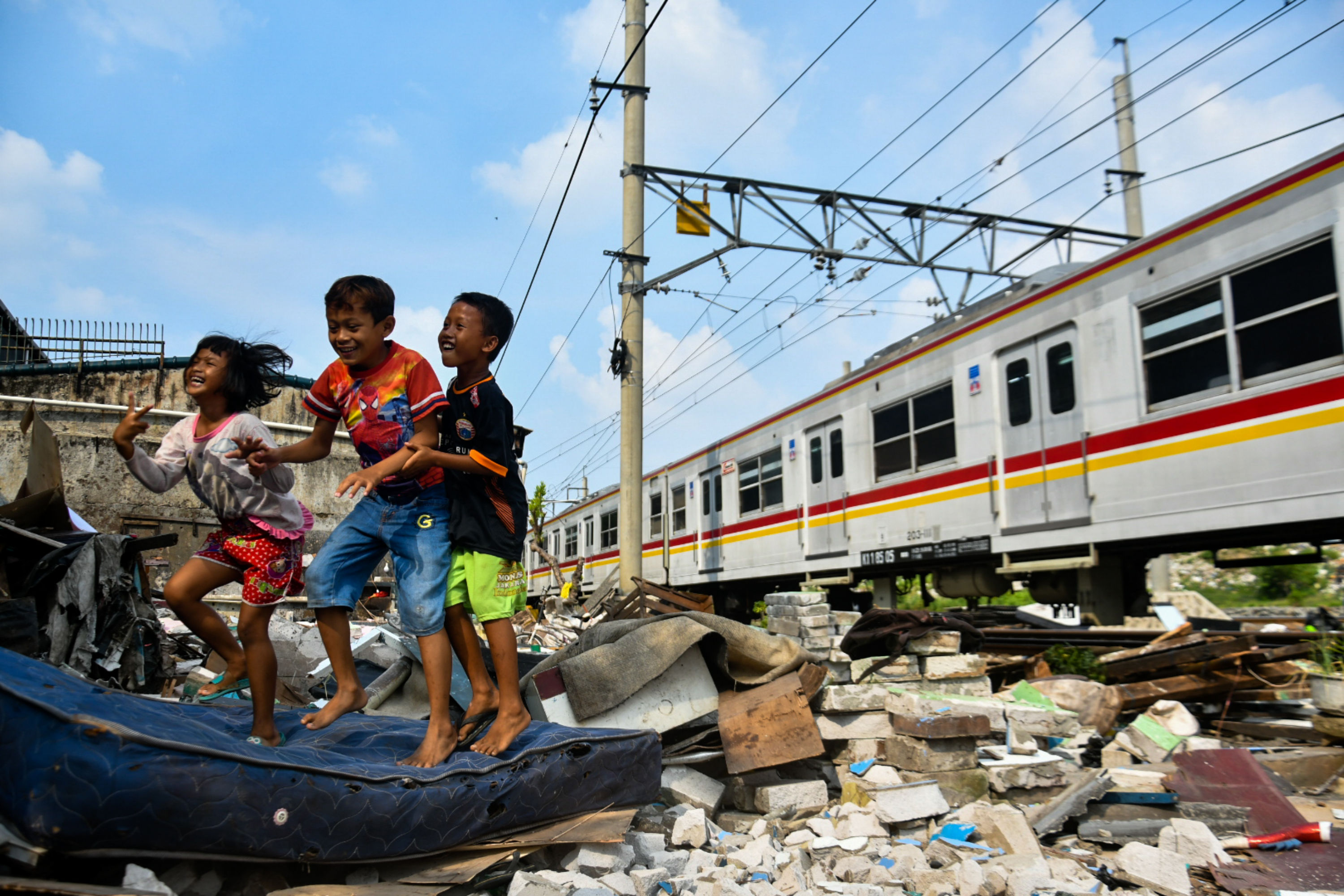 Anak-anak korban penggusuran asyik bermain saat KRL commuter line lewat.