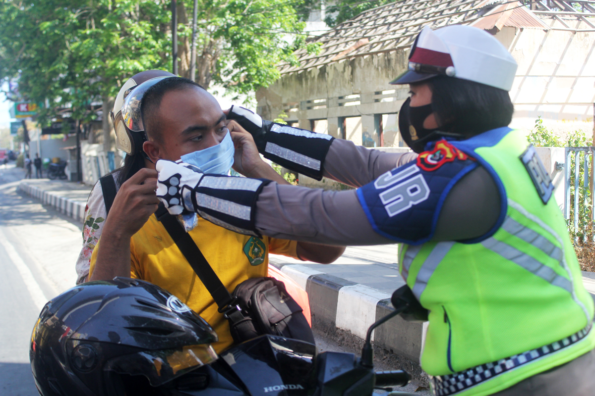 Seorang polisi mengenakan masker kepada pengendara motor di Kota Kupang, NTT, Kamis (10/9/2020)