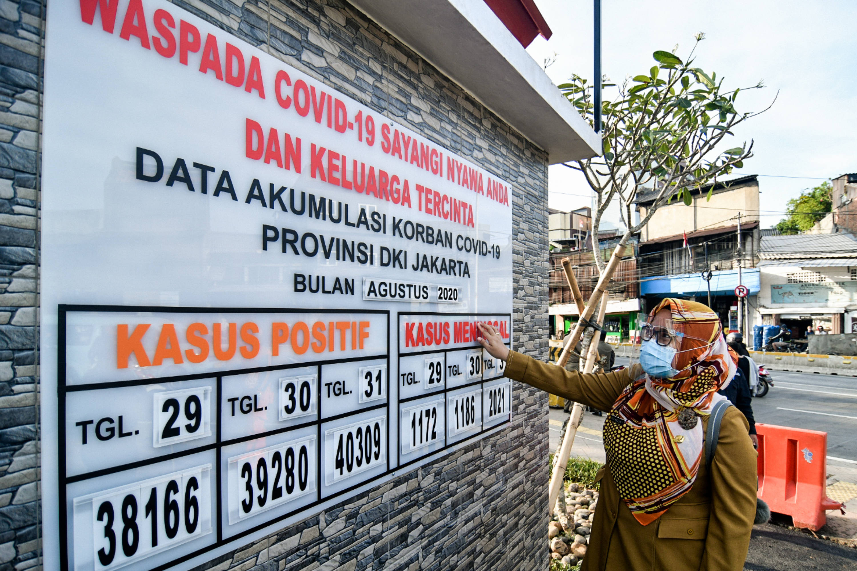 Seorang ASN Pemprov DKI melihat papan peringatan terkait covid-19.