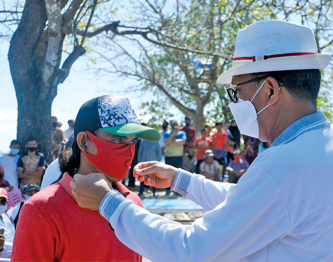 Gubernur Sulsel Nurdin Abdullah memasangkan masker kepada warga di Sulawesi Selatan.
