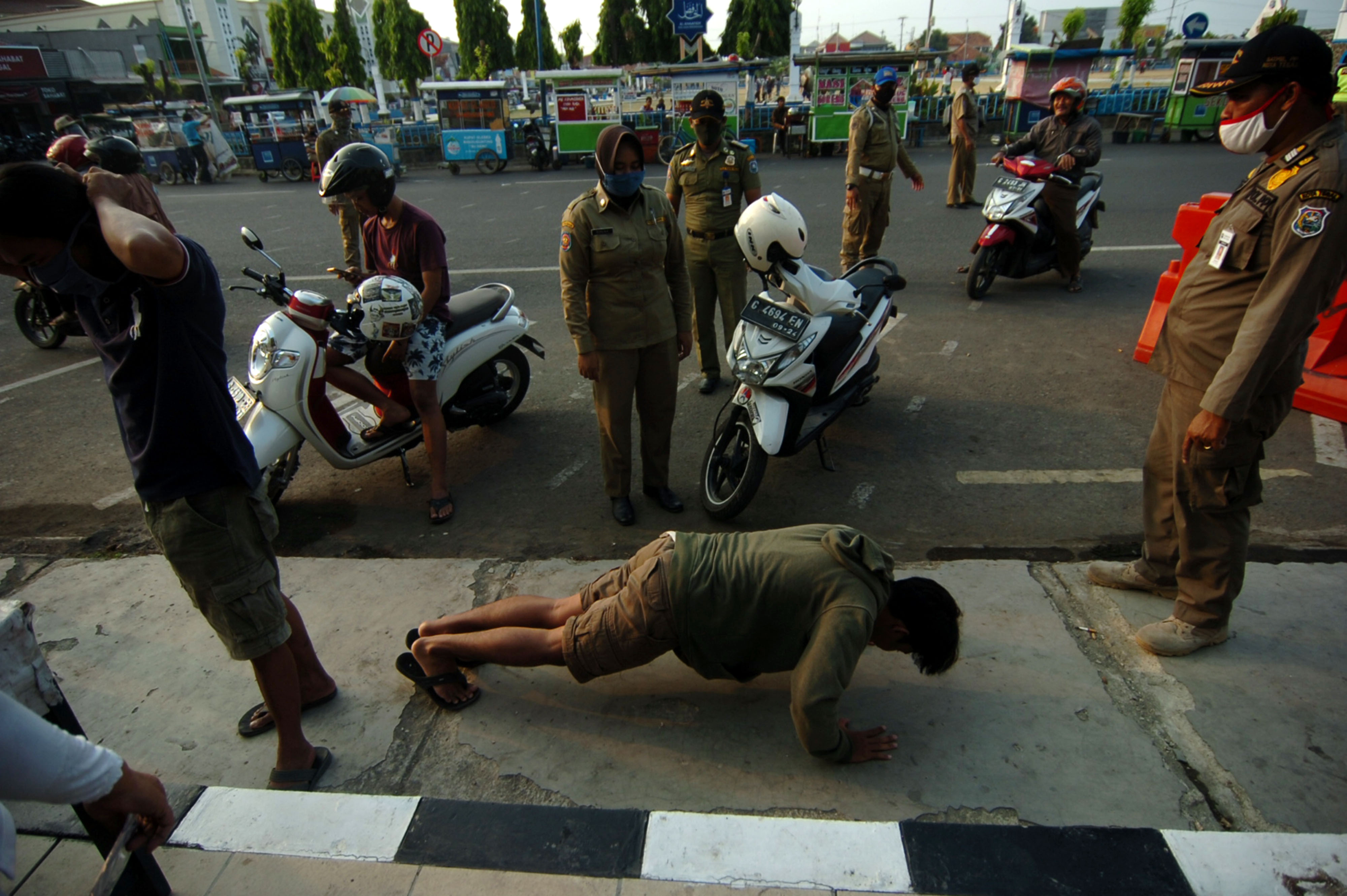 Petugas Satpol PP memberi sanksi push up kepada warga yang tidak mengenakan masker di Alun-alun Kota Tegal, Jawa Tengah, Senin (10/8/2020)