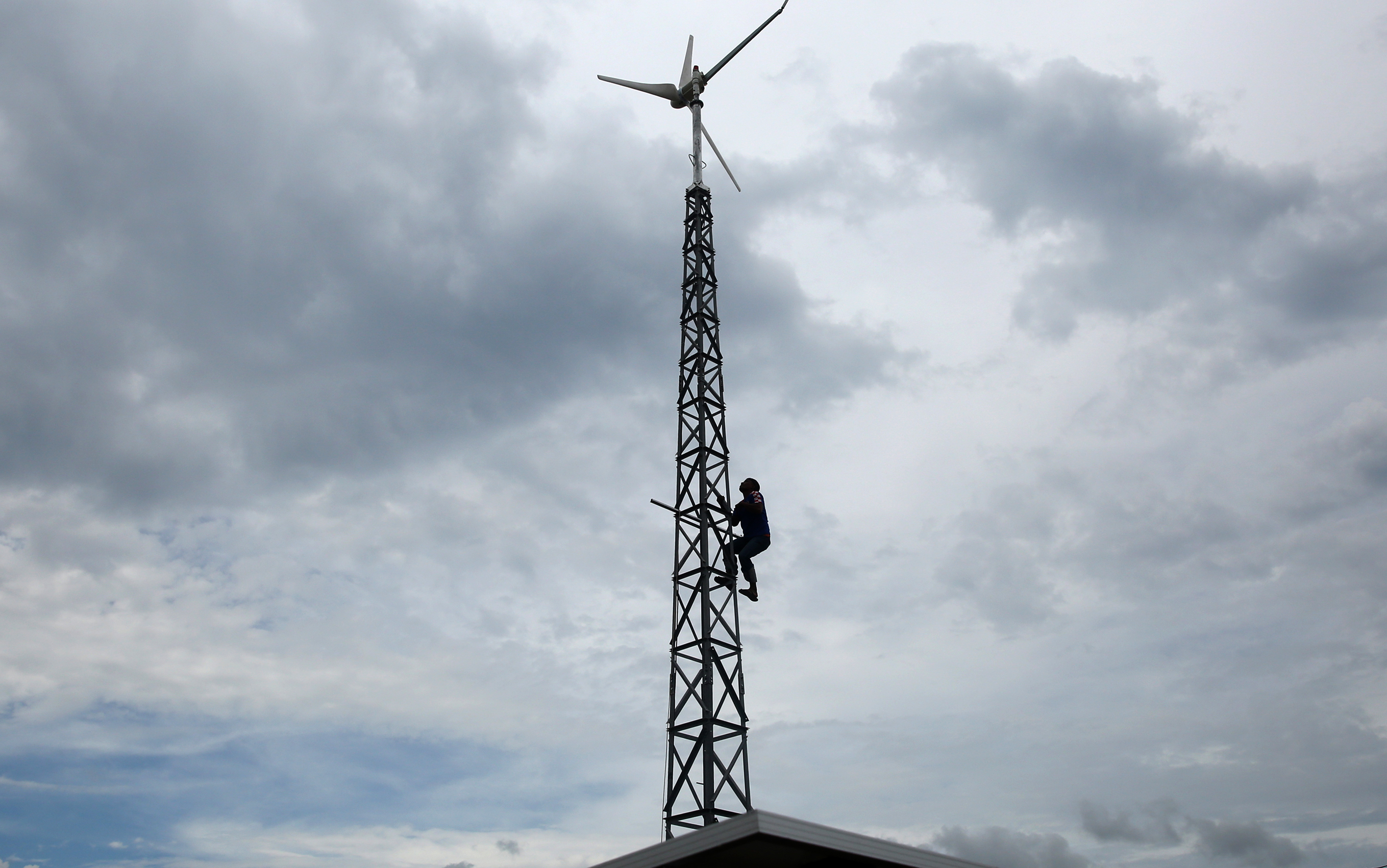 Pekerja menginspeksi tiang kincir pembangkit listrik tenaga hibrida (PLTH) surya dan angin di Krueng Raya, Kabupaten Aceh Besar, Aceh.