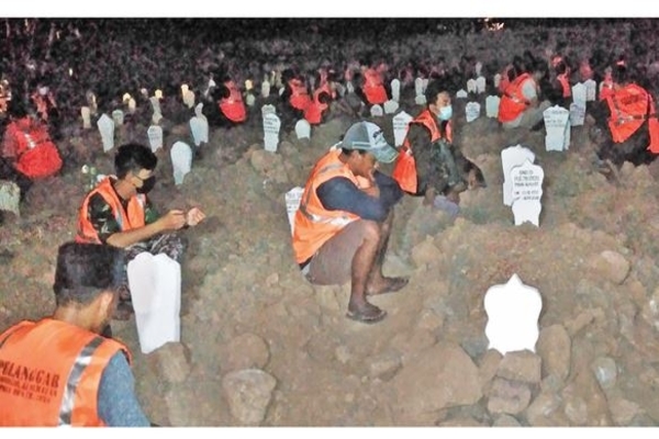 Para pelanggar protokol kesehatan berdoa bersama pada tengah malam di makam khusus korban covid-19, di Permakaman Delta Praloyo, Sidoarjo