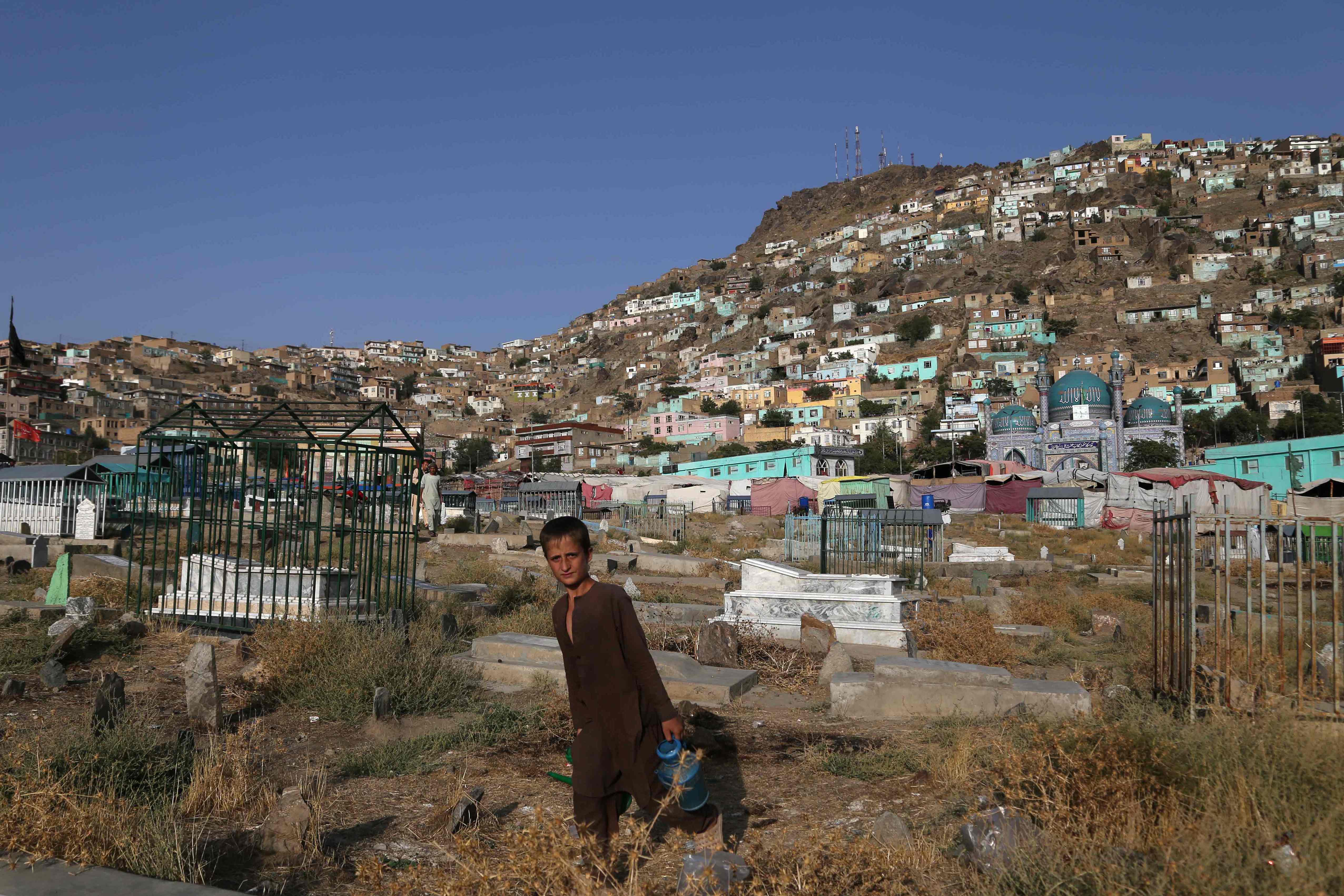 Seorang anak kecil berdiri dekat area pemakaman di Kabul, Afghanistan.