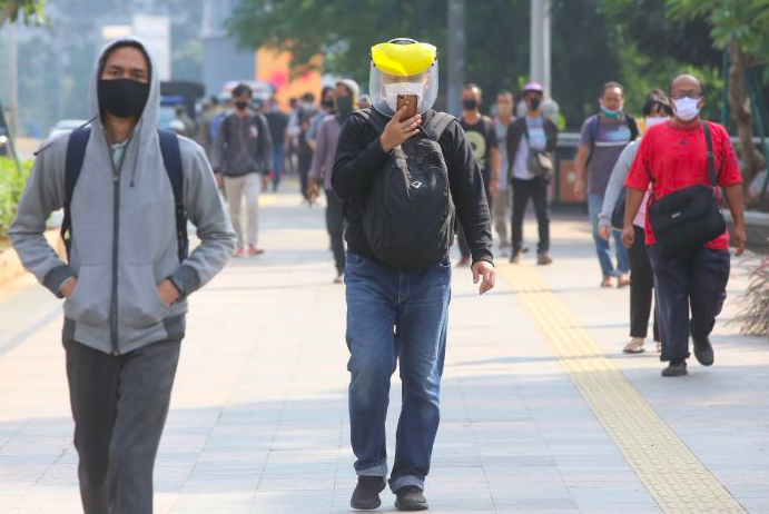 Para pekerja menuju kantor dengan menggunakan masker saat pandemik covid-19.