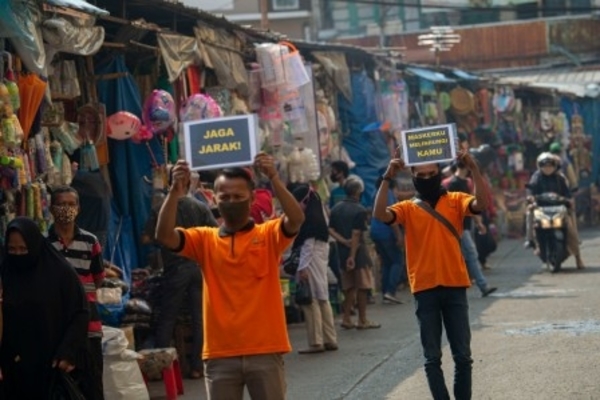 Petugas pengelola pasar berkampanye pencegahan covid-19 dengan membawa poster berisi pesan di Pasar Jatinegara, Jakarta, Kamis, 11 Juni 2020