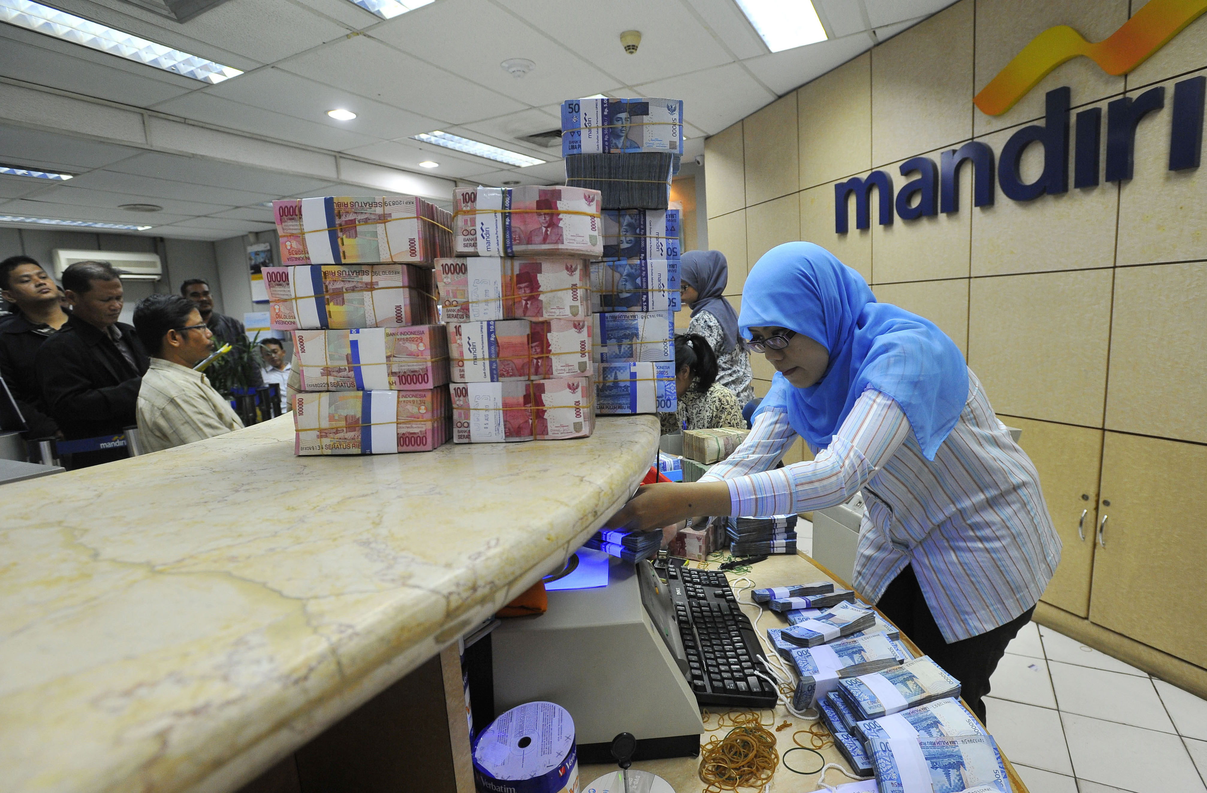 Petugas menghitung transaksi uang tunai di Bank Mandiri cabang Pertamina UPMS III Jakarta.