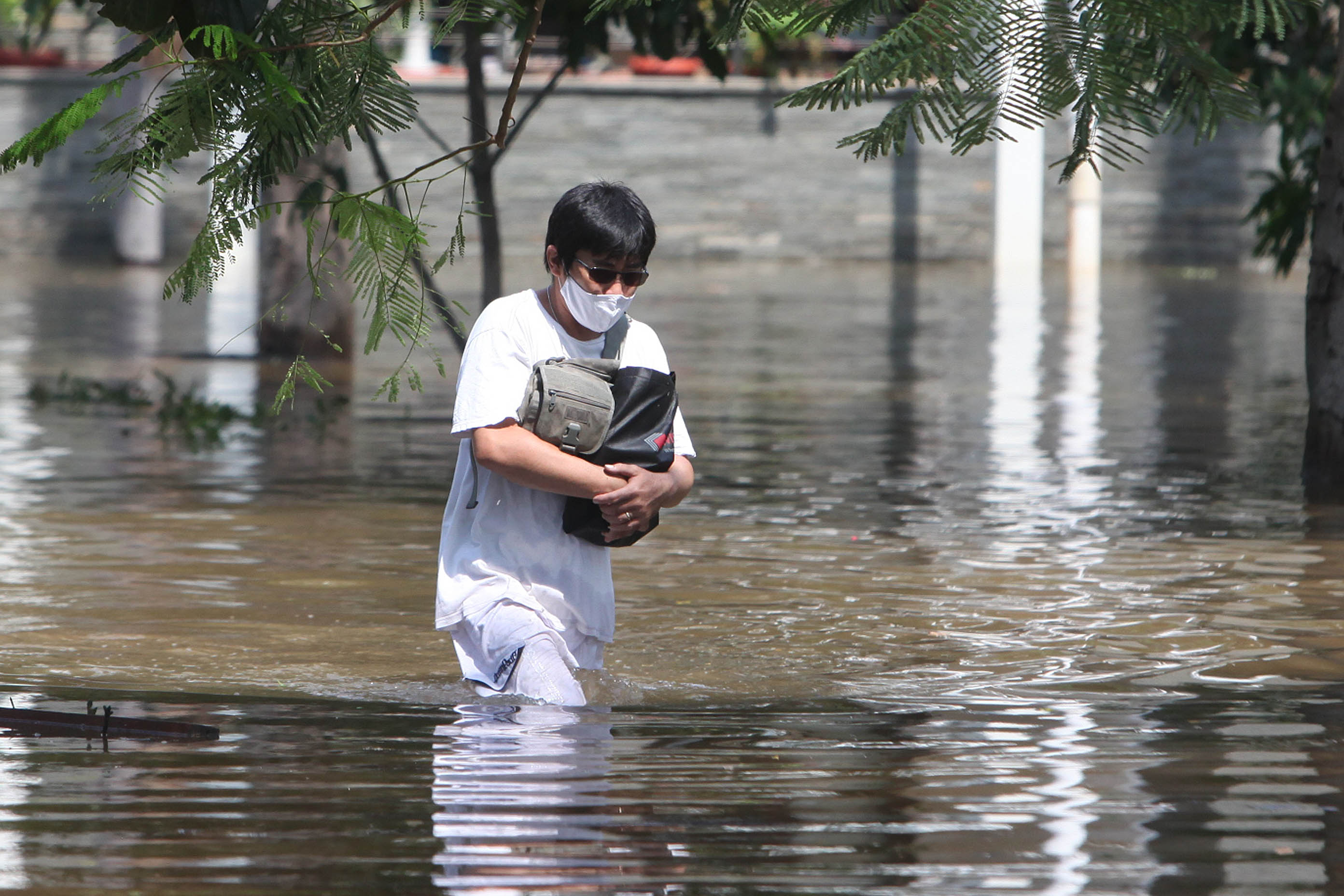Warga perumahan melintasi jalan yang banjir akibat naiknya air laut di kompleks perumahan mewah, Pantai Mutiara, Pluit, Jakarta Utara.