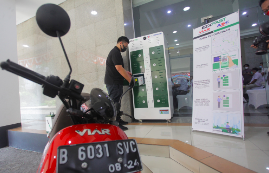 Petugas melakukan uji coba penggantian baterai sepeda motor listrik saat melakukan uji coba Stasiun Penukaran Baterai Kendaraan Listrik Umum