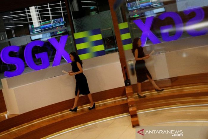 Seorang pekerja melintas di logo SGX (Singapore Stock Exchange). 