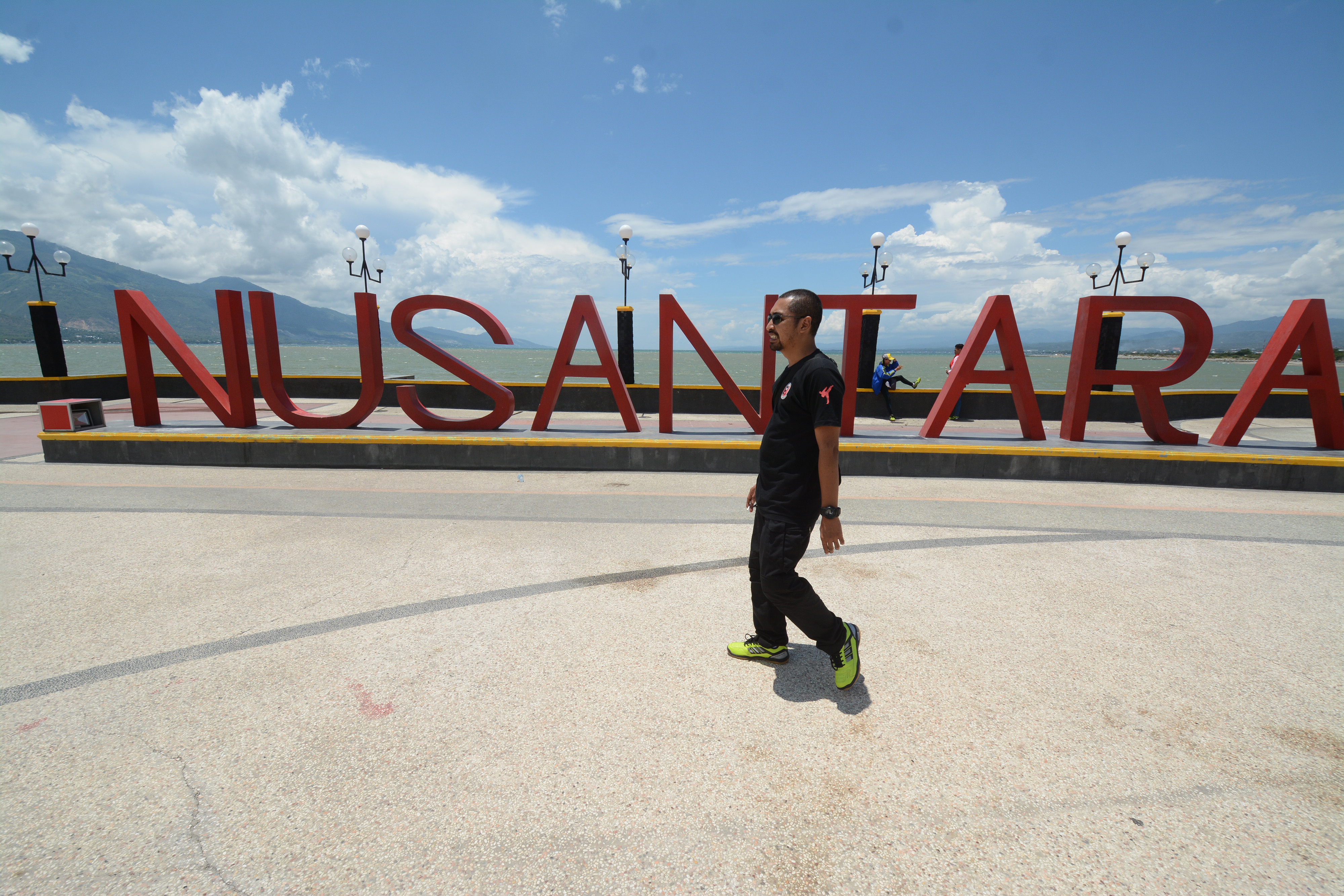 Warga melintas dengan bayangan dirinya yang pendek tegak lurus di Anjungan Nusantara, Teluk Palu, Sulawesi Tengah, Rabu (21/3/2018).
