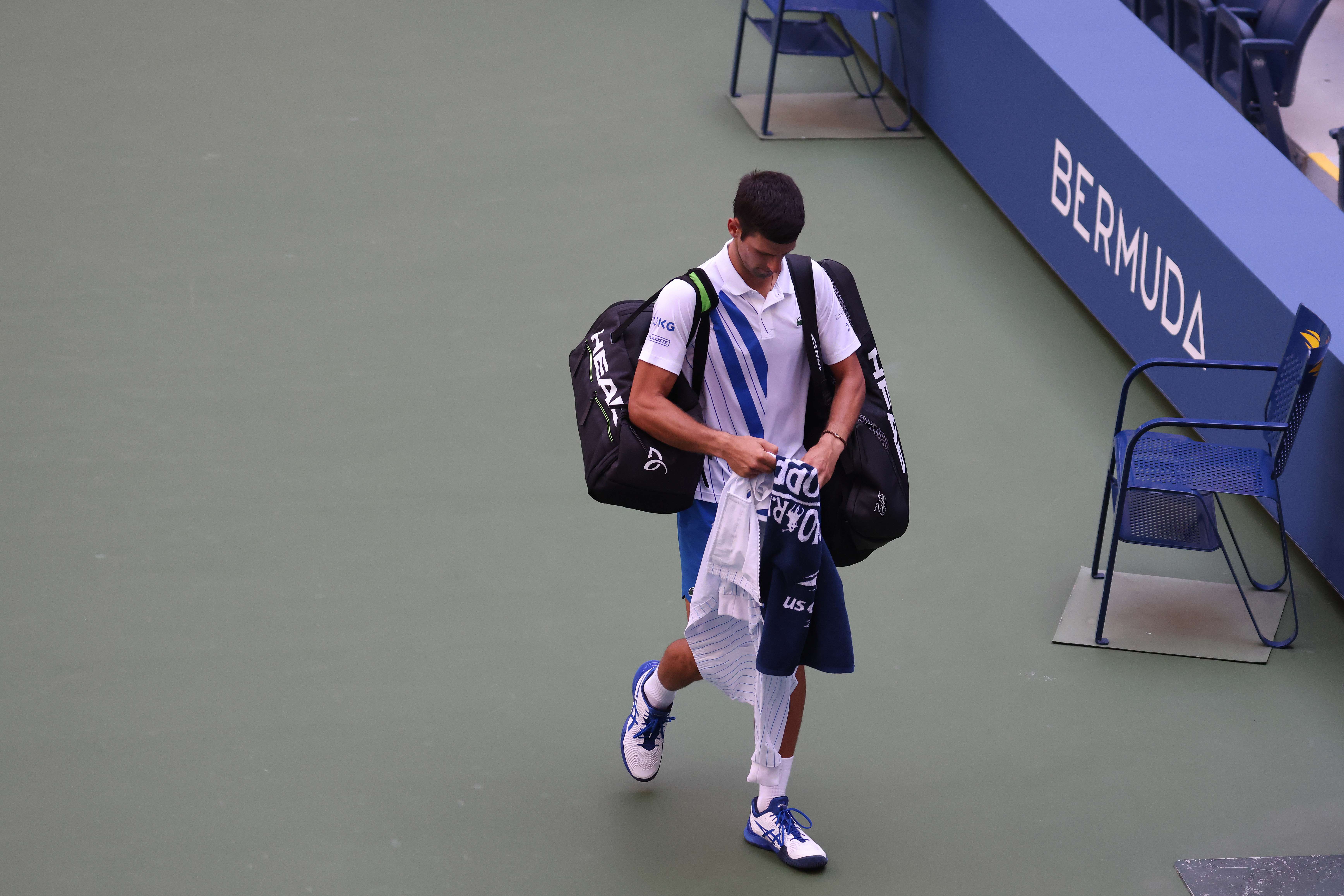 Novak Djokovic berjalan meninggalkan lapangan setelah didiskualifikasi di AS Terbuka.