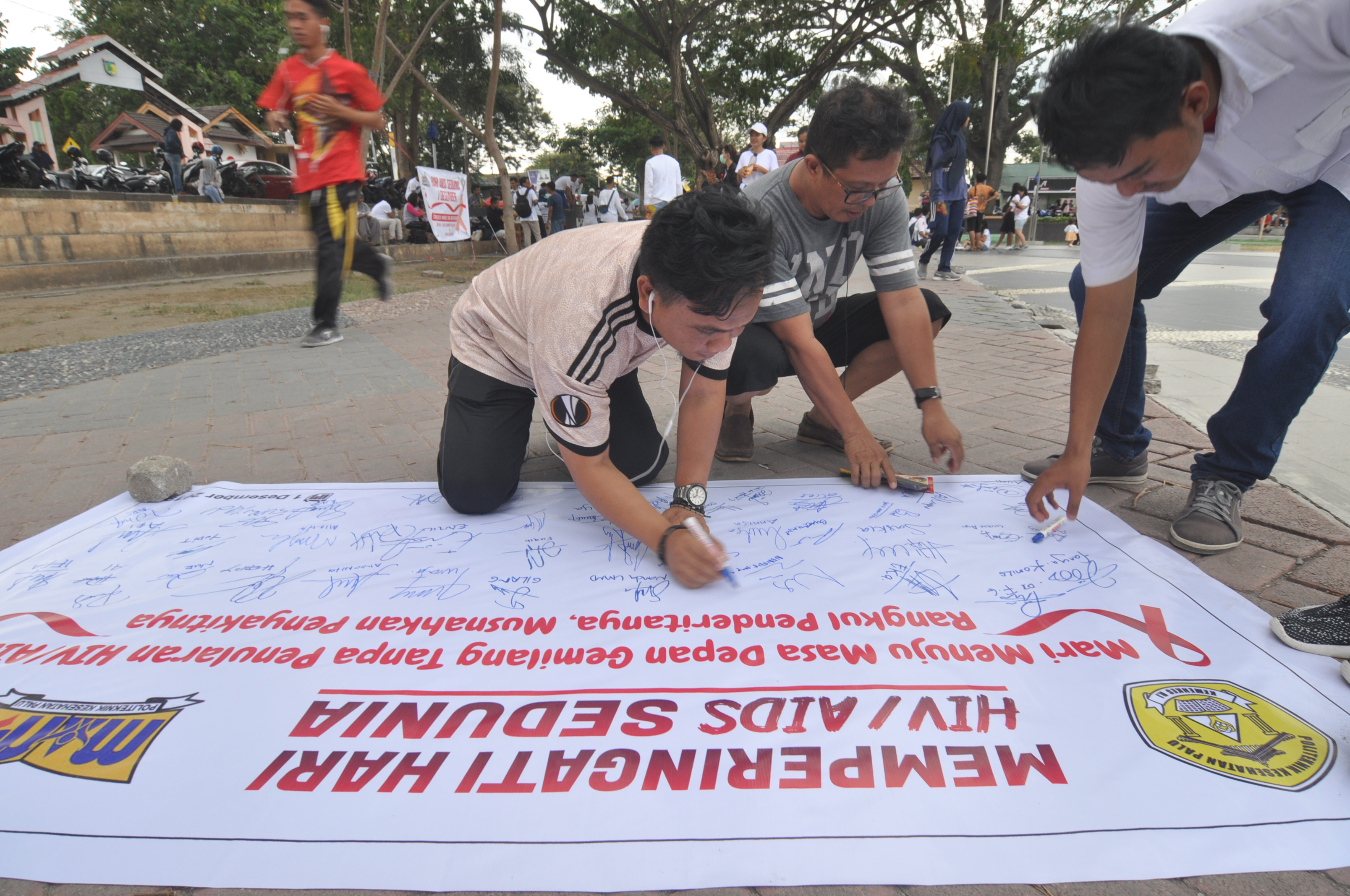 Sejumlah warga membubuhkan tanda tangan pada peringatan Hari Aids Sedunia di Lapangan Vatulemo, Palu, Sulawesi Tengah, Minggu (1/12/2019).