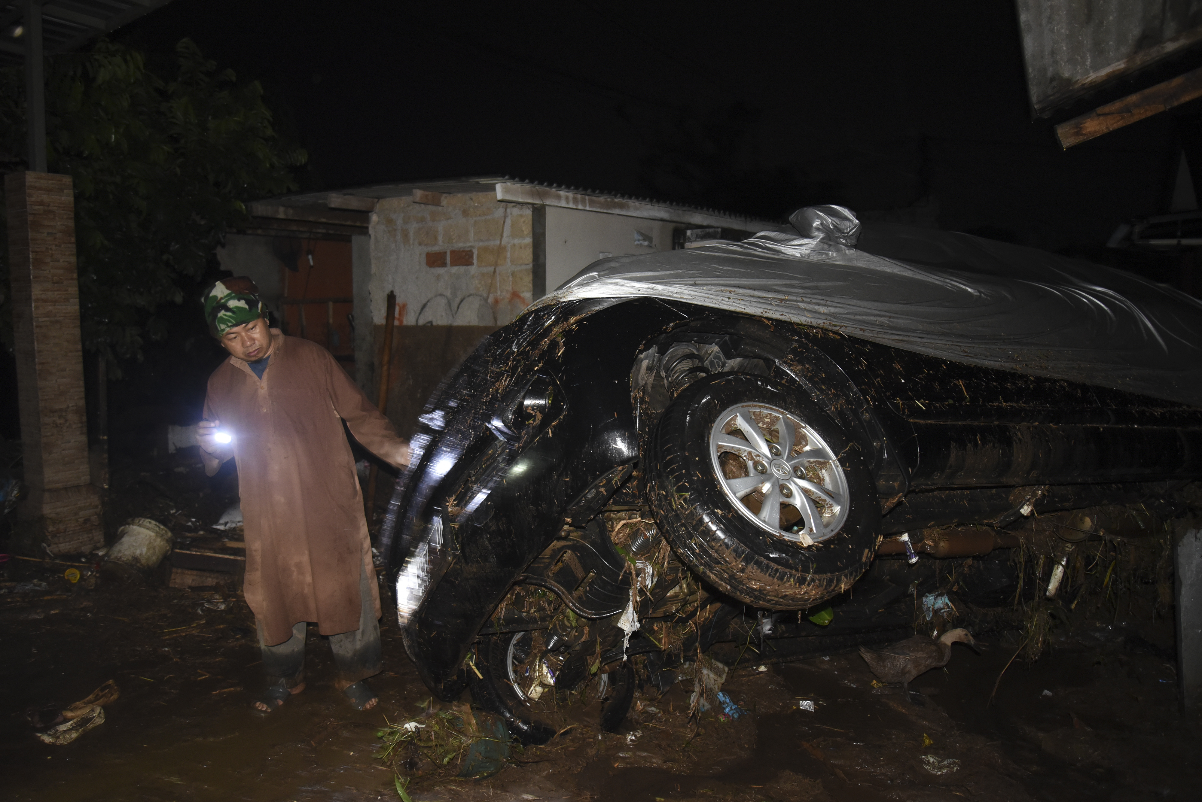 Petugas memeriksa kondisi kendaraan yang terbawa arus banjir bandang di Desa Mekarsari, Kecamatan Cicurug, Kabupaten Sukabumi.