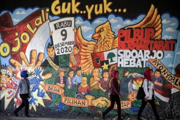 Ilustrasi -- Warga berjalan di depan mural Pemilu 2020 di kawasan Jati Raya, Sidoarjo, Jawa Timur, Jumat, 28 Agustus 2020. 