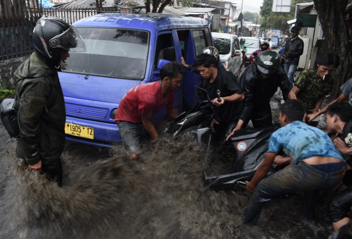 Sejumlah warga menolong motor yang tersangkut angkot akibat terseret banjir di Jl. Cihanjuang, Paronppong, Bandung Barat, Selasa (22/9)