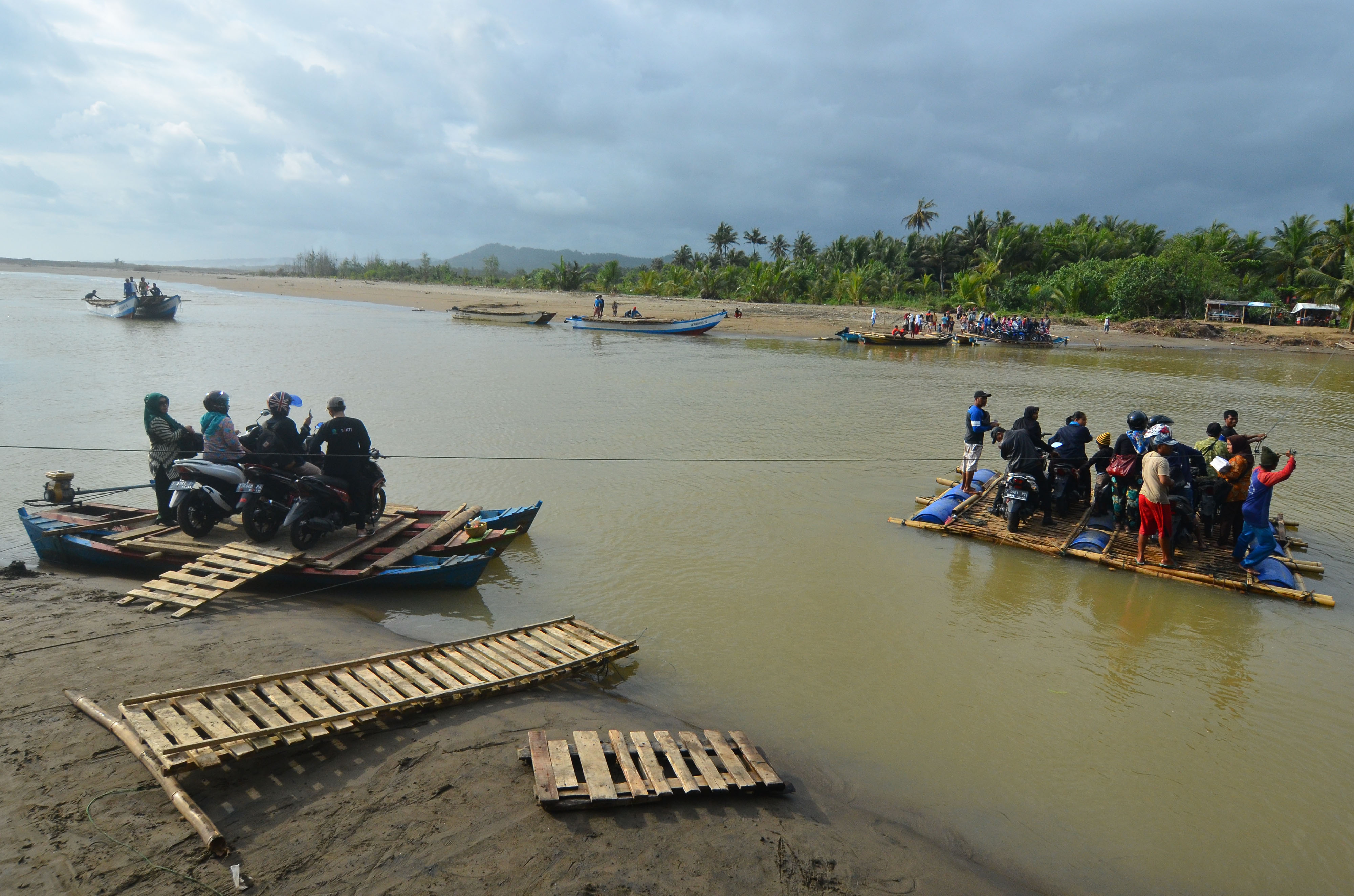 Warga bersama kendaraan bermotor menyeberangi sungai menggunakan perahu di Sungai Muara Cipatujah, Kabupaten Tasikmalaya, Jawa Barat