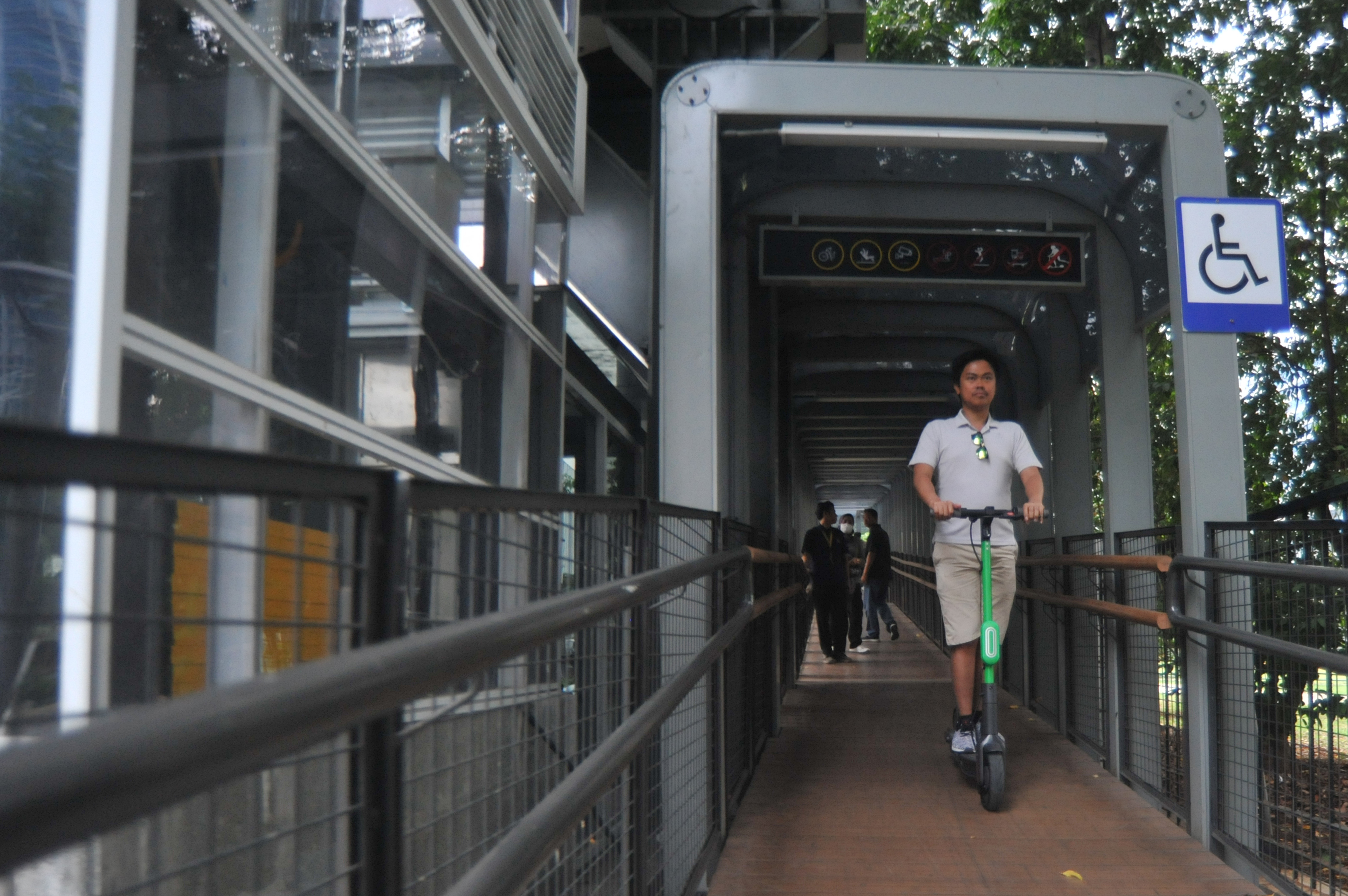 Warga menggunakan skuter listrik melewati Jembatan Penyeberangan Orang (JPO) Gelora Bung Karno