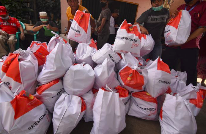 Petugas dibantu warga menurunkan paket sembako Kemensos di Kebon Baru, Tebet, Jakarta.