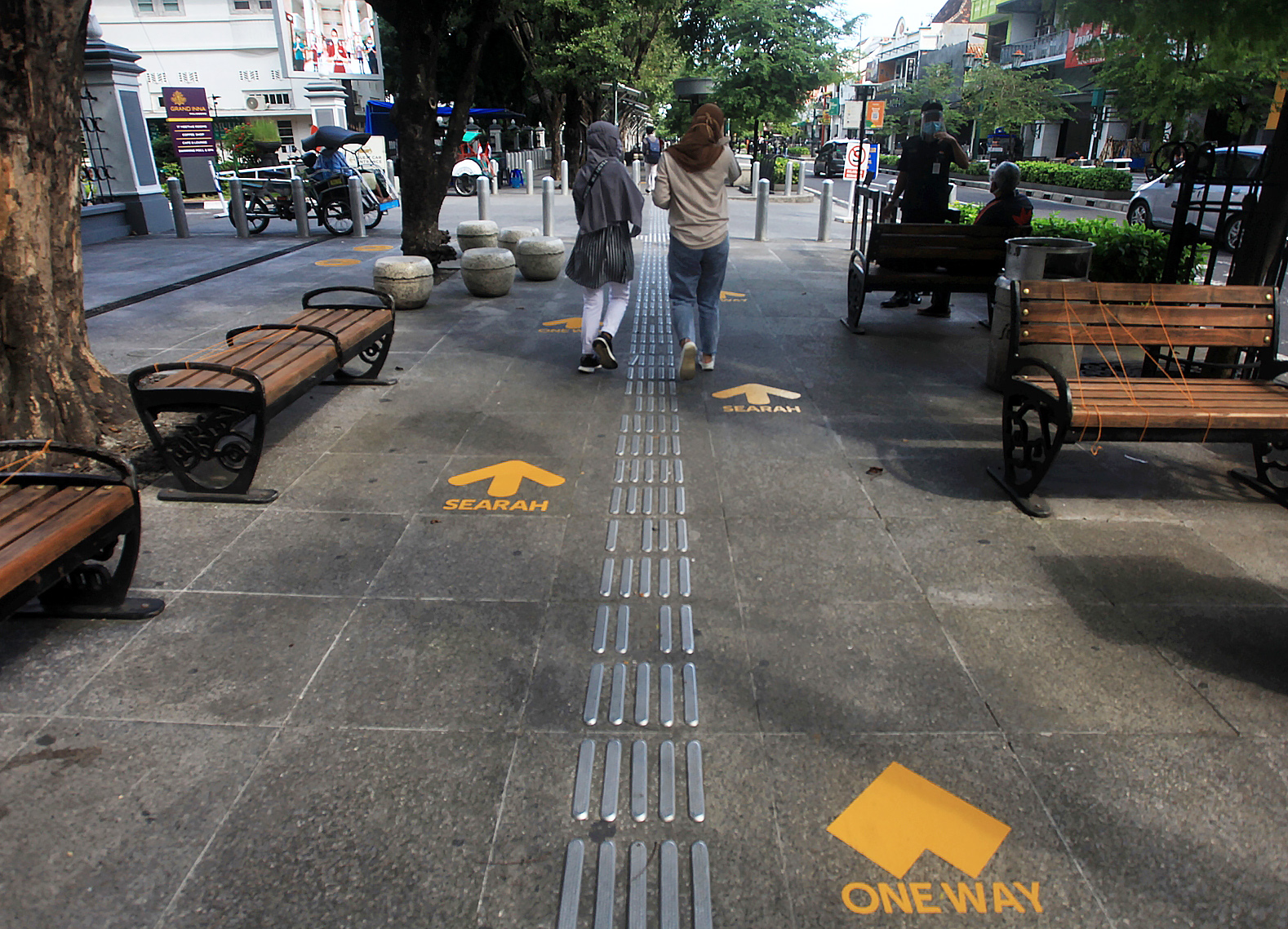 Pengunjung melintas di dekat tanda jaga jarak dan jalan satu arah di Kawasan Wisata Malioboro, Yogyakarta, Kamis (18/6/2020)