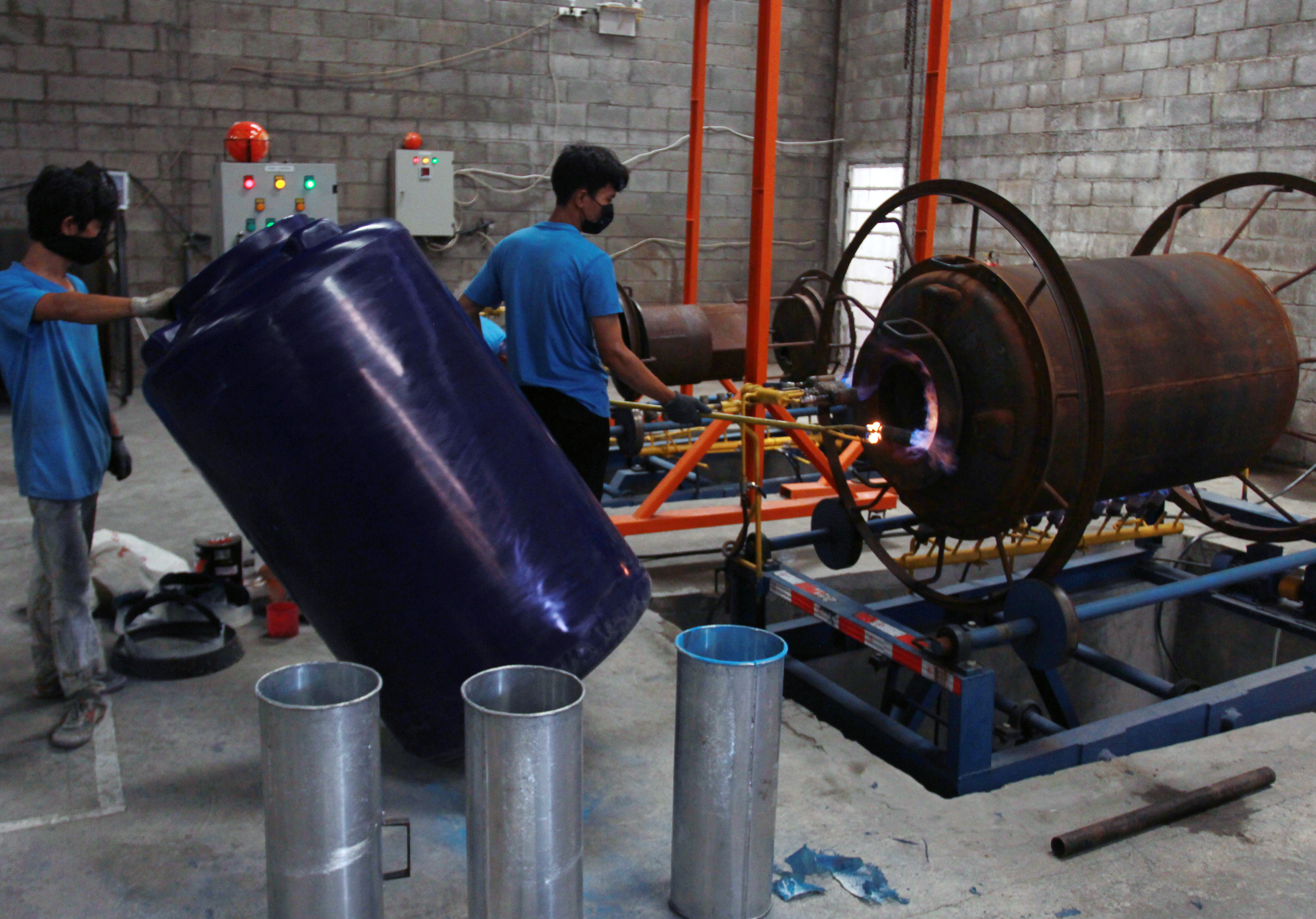 Pekerja melakukan proses pemuaian bahan baku pembuatan tangki air di sebuah pabrik pembuatan tangki air, kawasan Pasar Kemis, Tangerang.