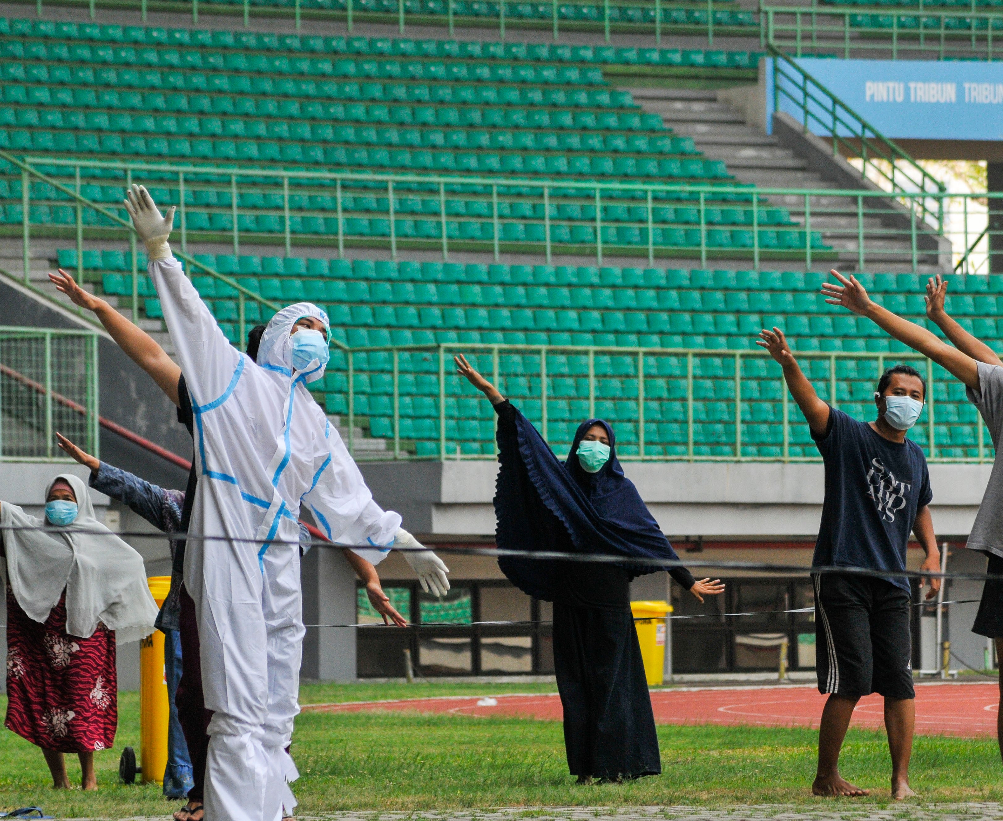 Petugas medis (kiri) memimpin senam pagi bersama pasien covid-19 berstatus Orang Tanpa Gejala di Stadion Patriot Chandrabhaga, Bekasi.