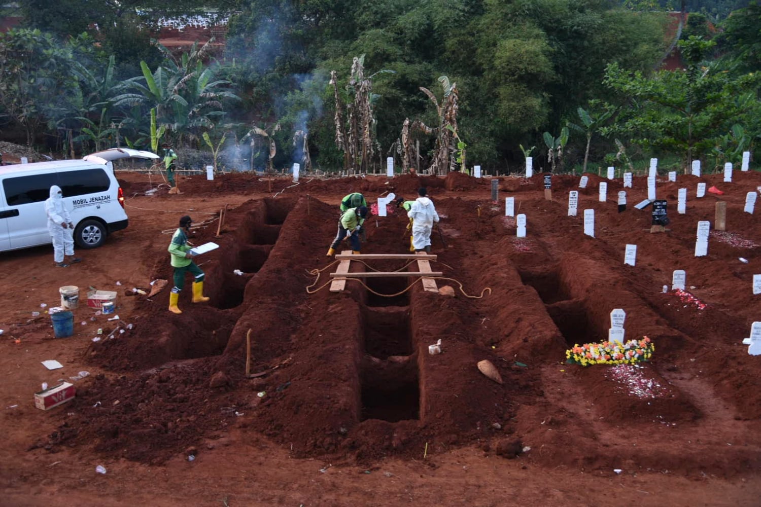 Petugas memakamkan jenazah pasien covid-19 dengan protokol kesehatan di TPU Pondok Rangon, Jakarta.