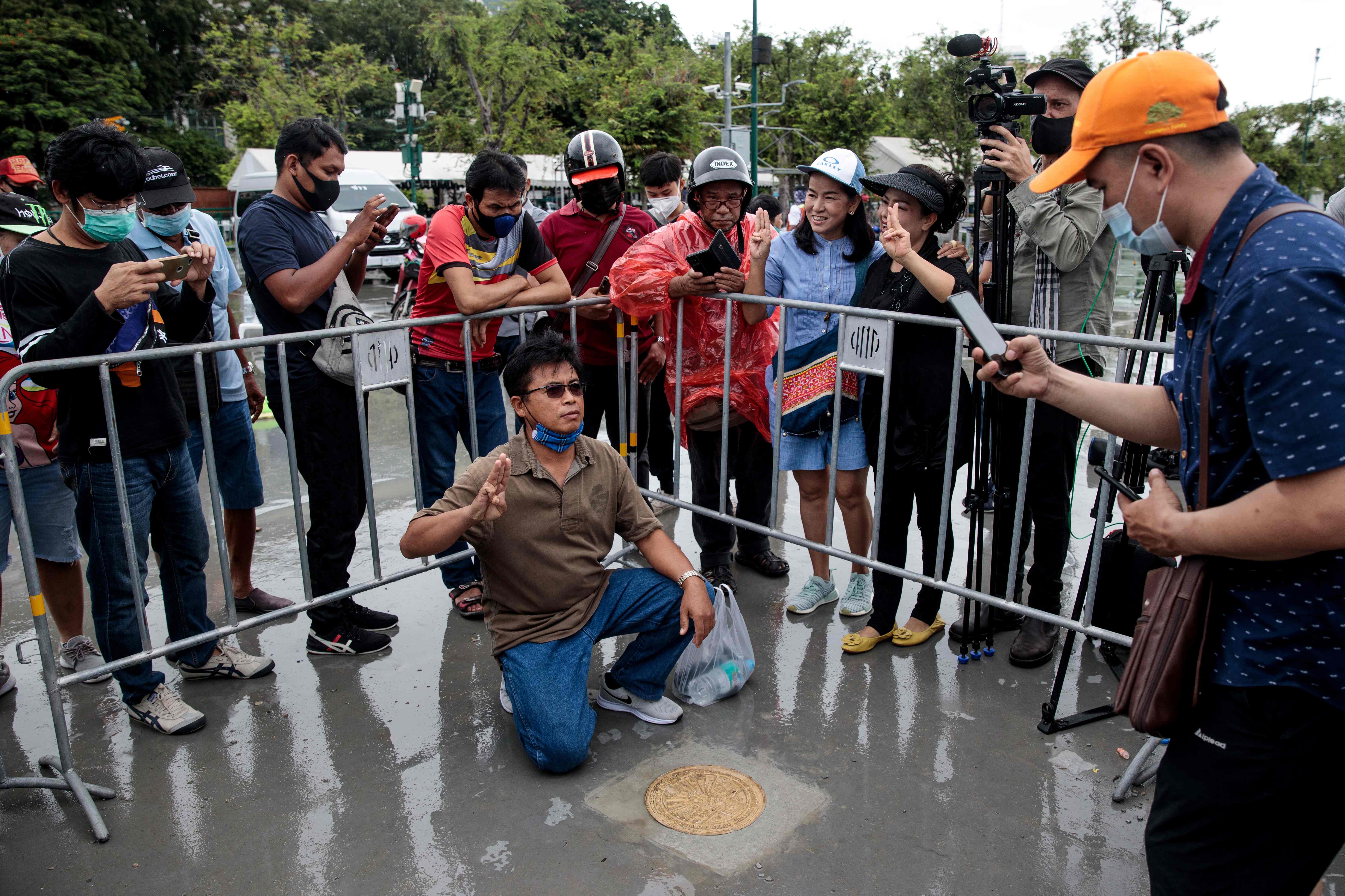 Warga Thailand berpose dengan plakat yang dipasang aktivis prodemokrasi di dekat Lapangan Sanam Luang, Bangkok.