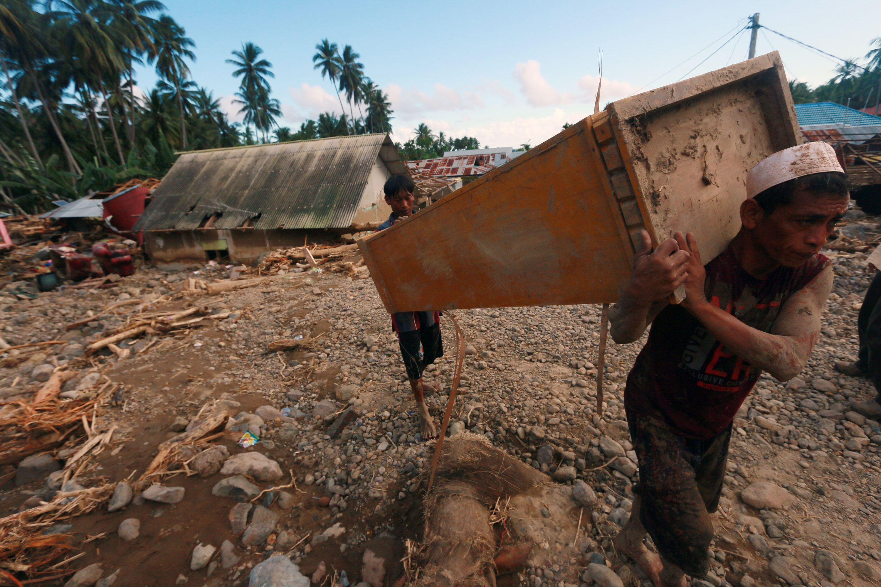 Warga korban banjir menyelamatkan sisa perabot yang terdampak banjir bandang di Gorontalo.