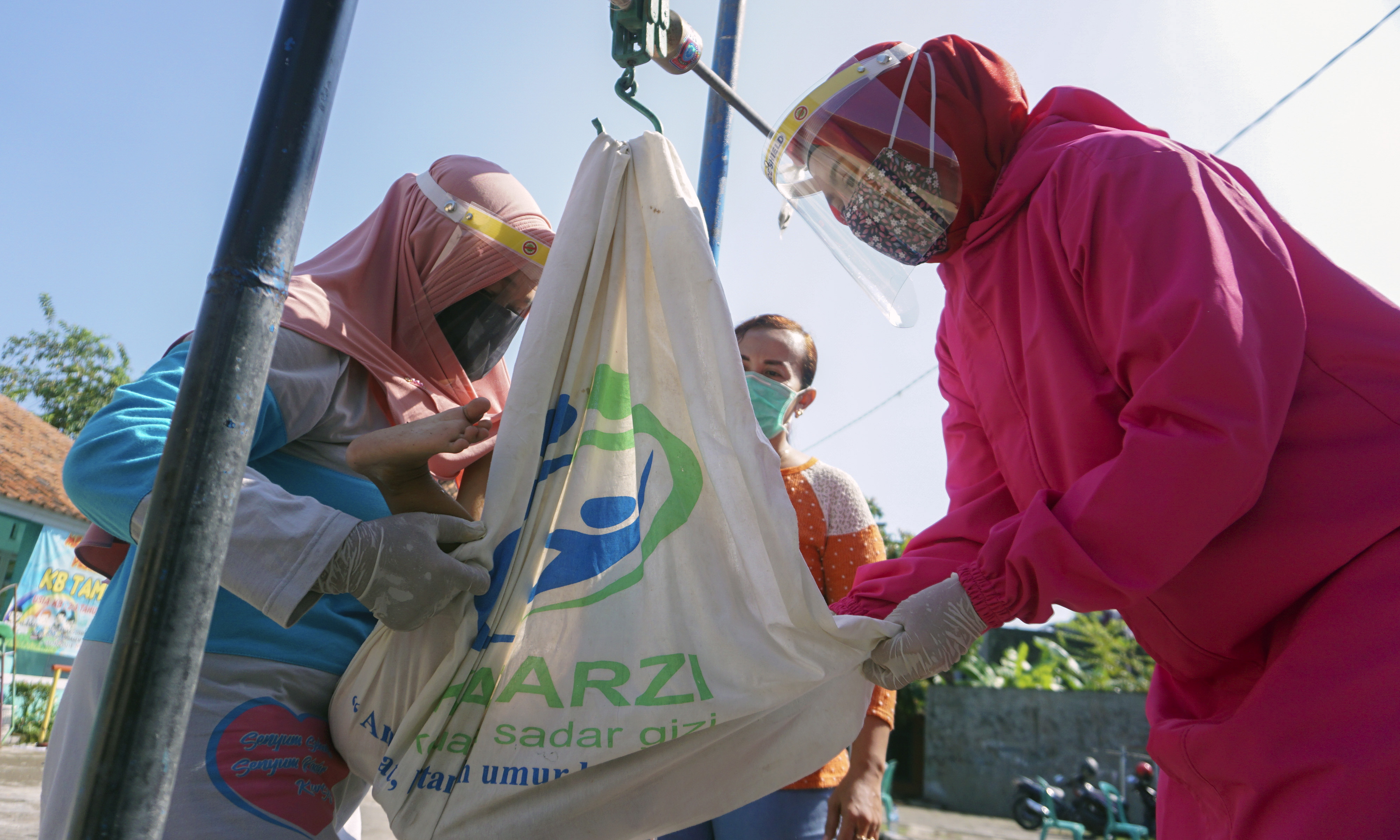 Petugas kesehatan mengukur berat badan balita saat kegiatan pos pelayanan terpadu (posyandu) di Posyandu.