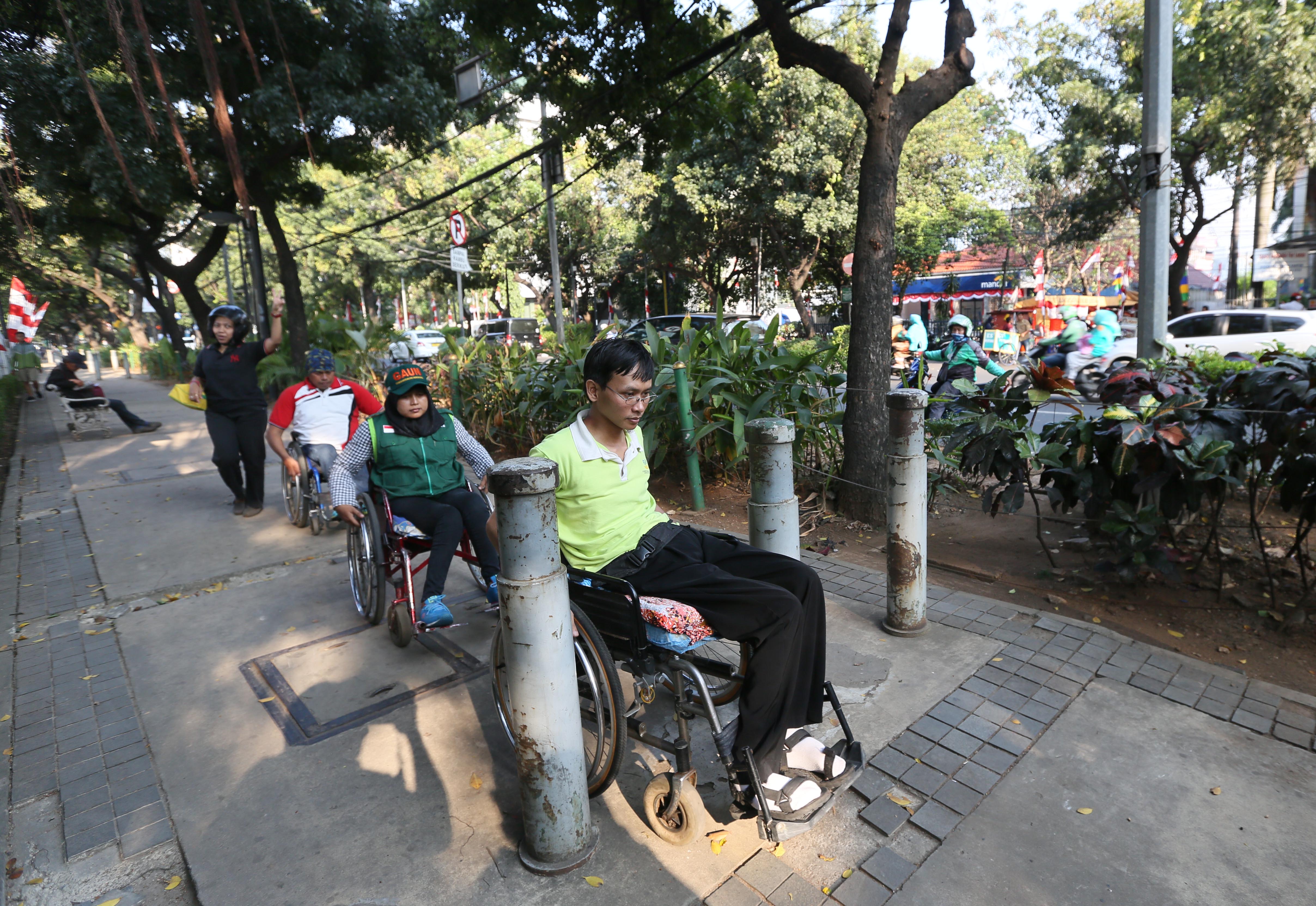 Aktivis tuna netra dan pengguna kursi roda memantau fasilitas akses pedestrian untuk disabilitas di kawasan Kebon Sirih, Jakarta.