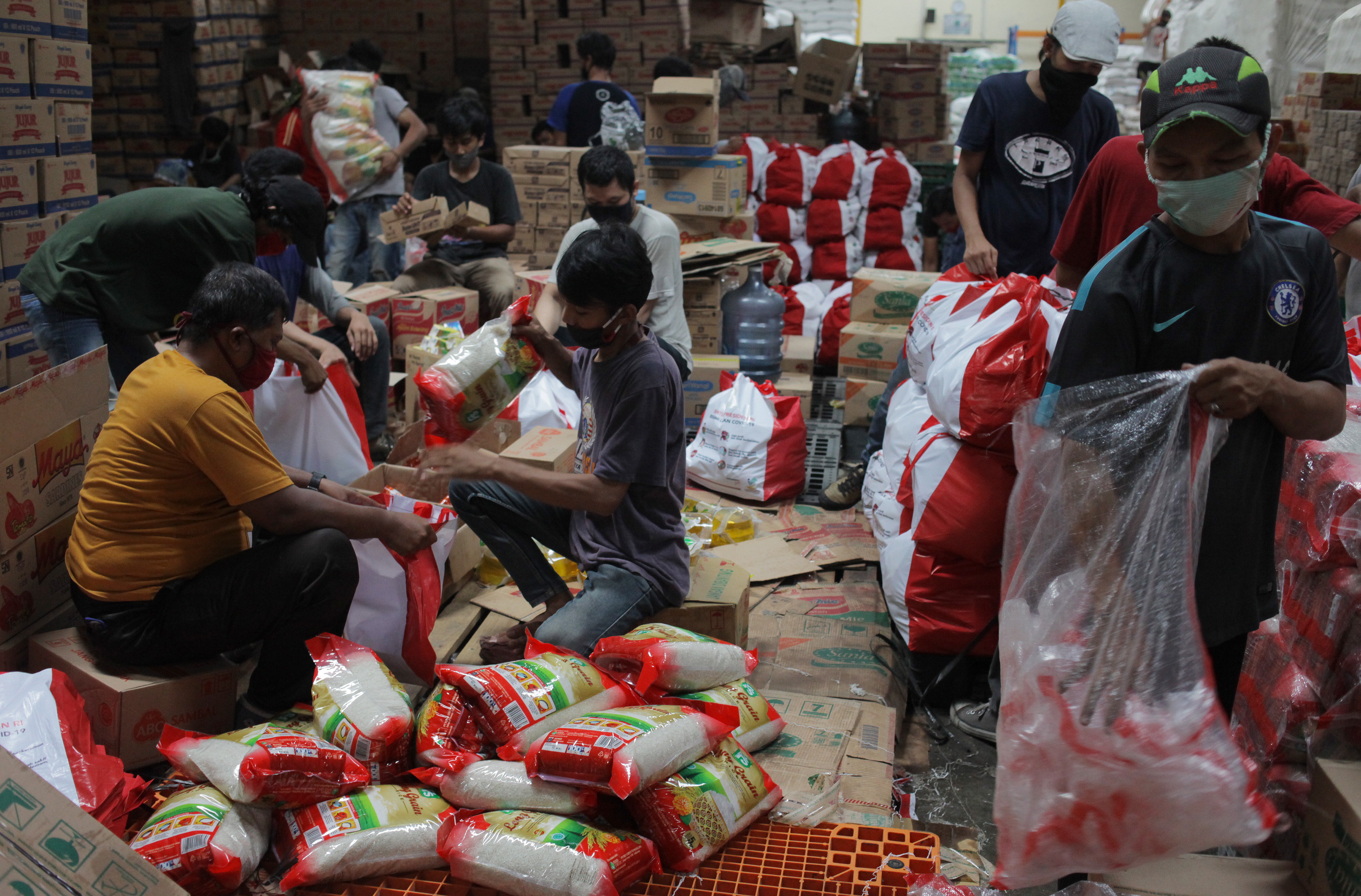 Pekerja mengemas paket bantuan sosial di gudang Food Station, Cipinang, Jakarta