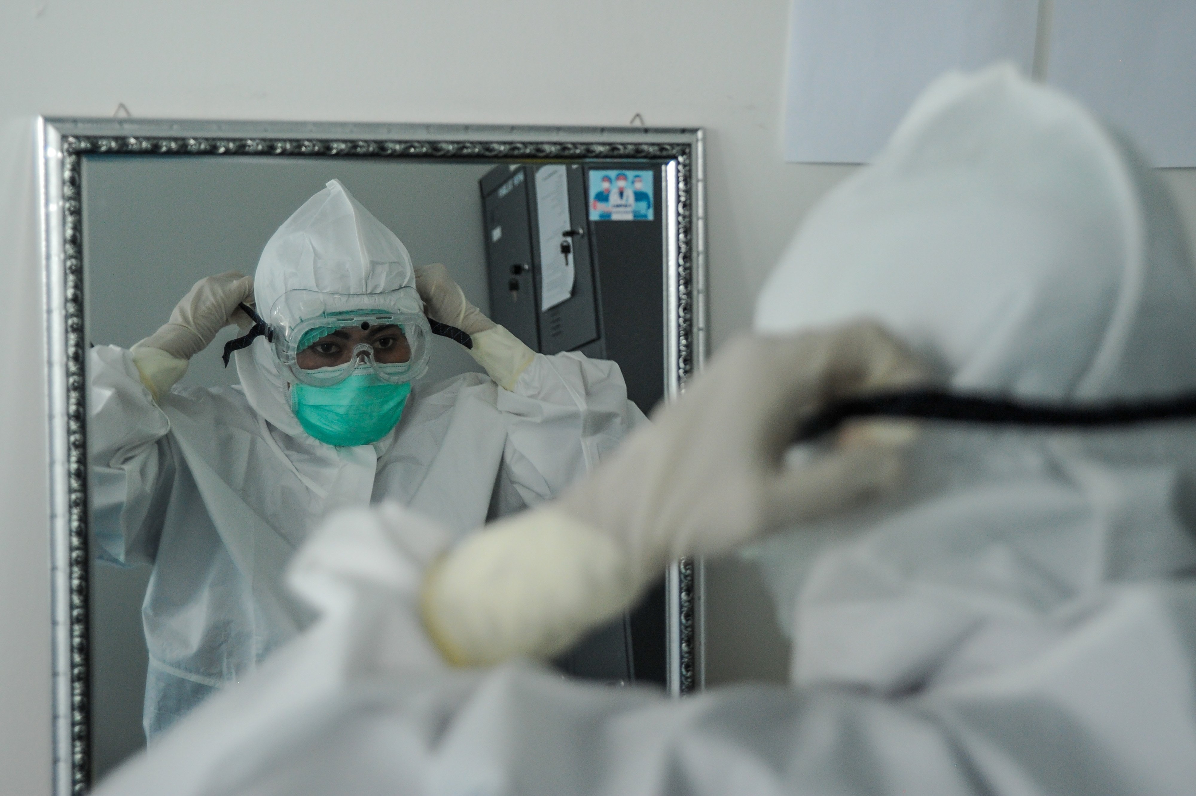  Seorang tenaga kesehatan memakai alat pelindung diri