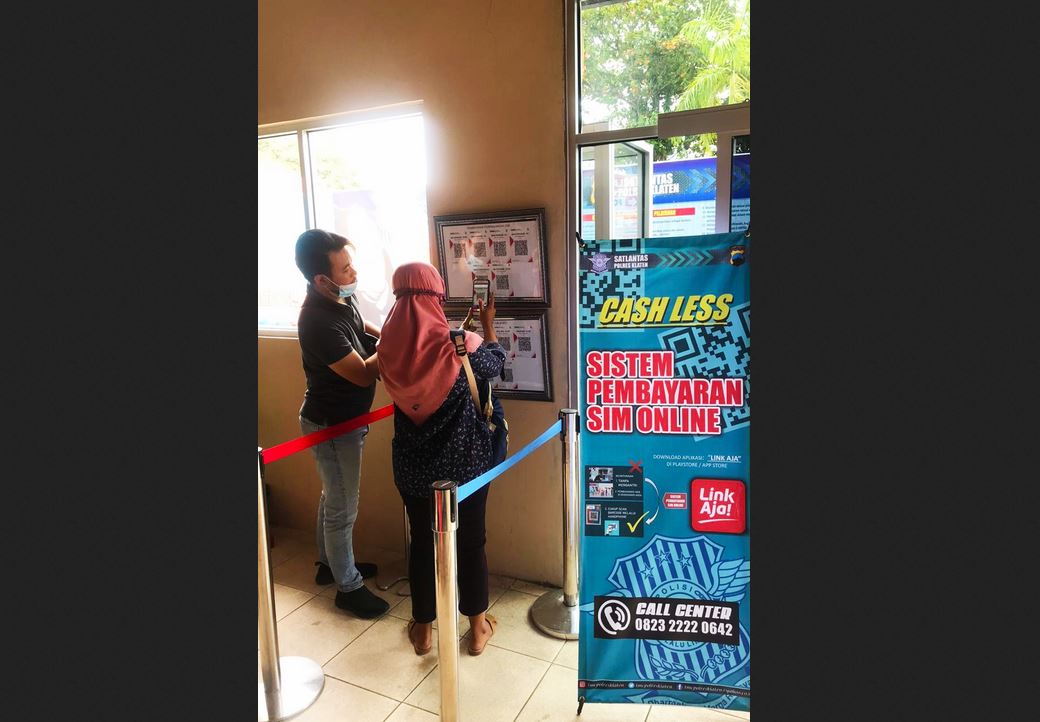 Pemohon SIM men-scan barcode untuk pembayaran biaya SIM di Satpas Satlantas Polres Klaten.