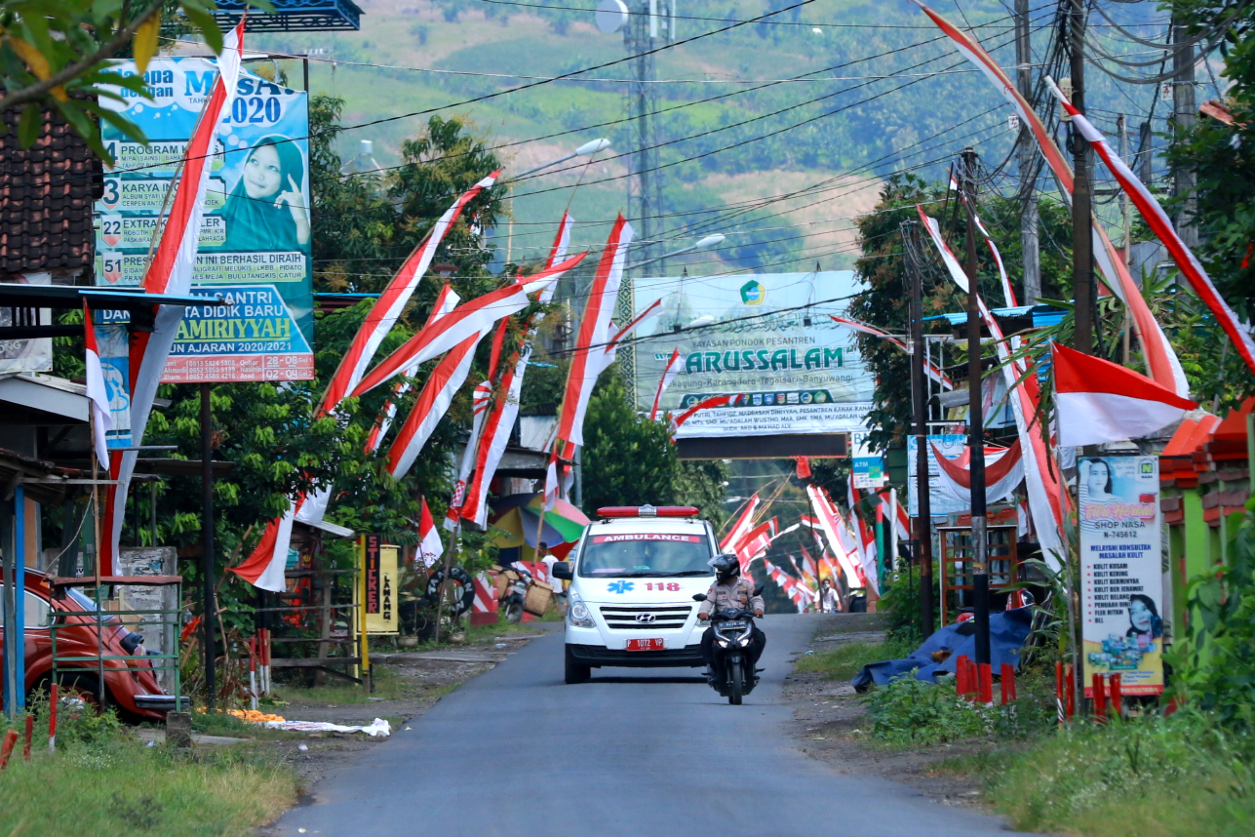 Anggota polisi mengawal mobil ambulans di jalan masuk Pondok Pesantren Darussalam Blokagung, Banyuwangi, Jawa Timur, Rabu (2/9)
