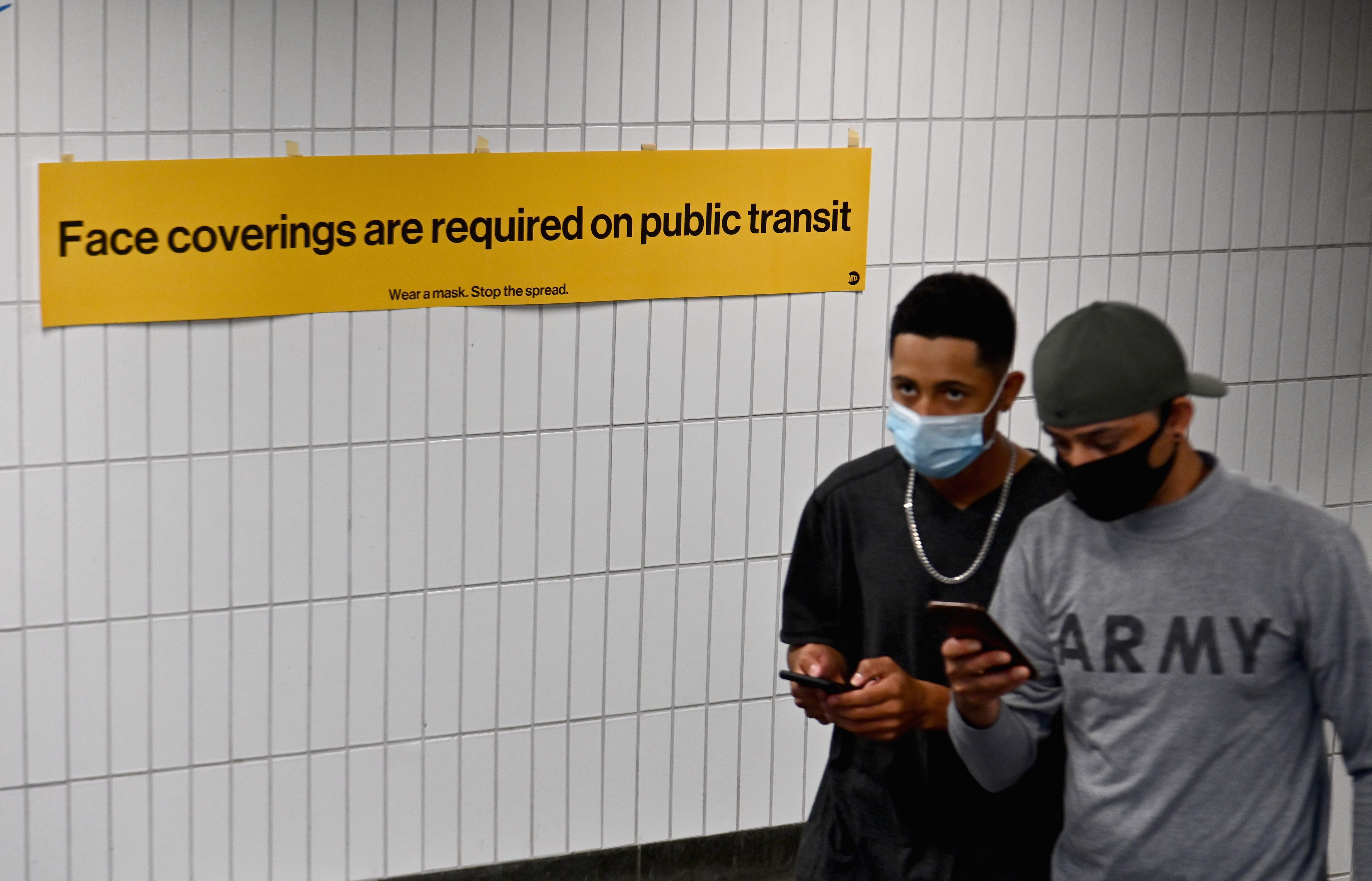 Dua warga mengenakan masker saat keluar dari stasiun kereta bawah tanah di New York, Amerika Serikat.