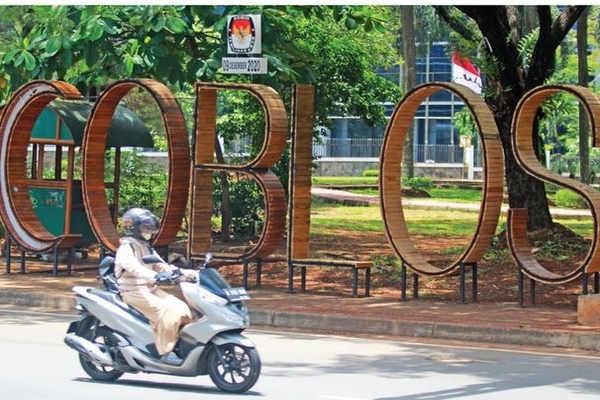 Ilustrasi -- Pengendara motor melintas di depan ornamen bertuliskan ‘coblos’ yang merupakan alat sosialisasi pilkada di Serpong, Tangsel