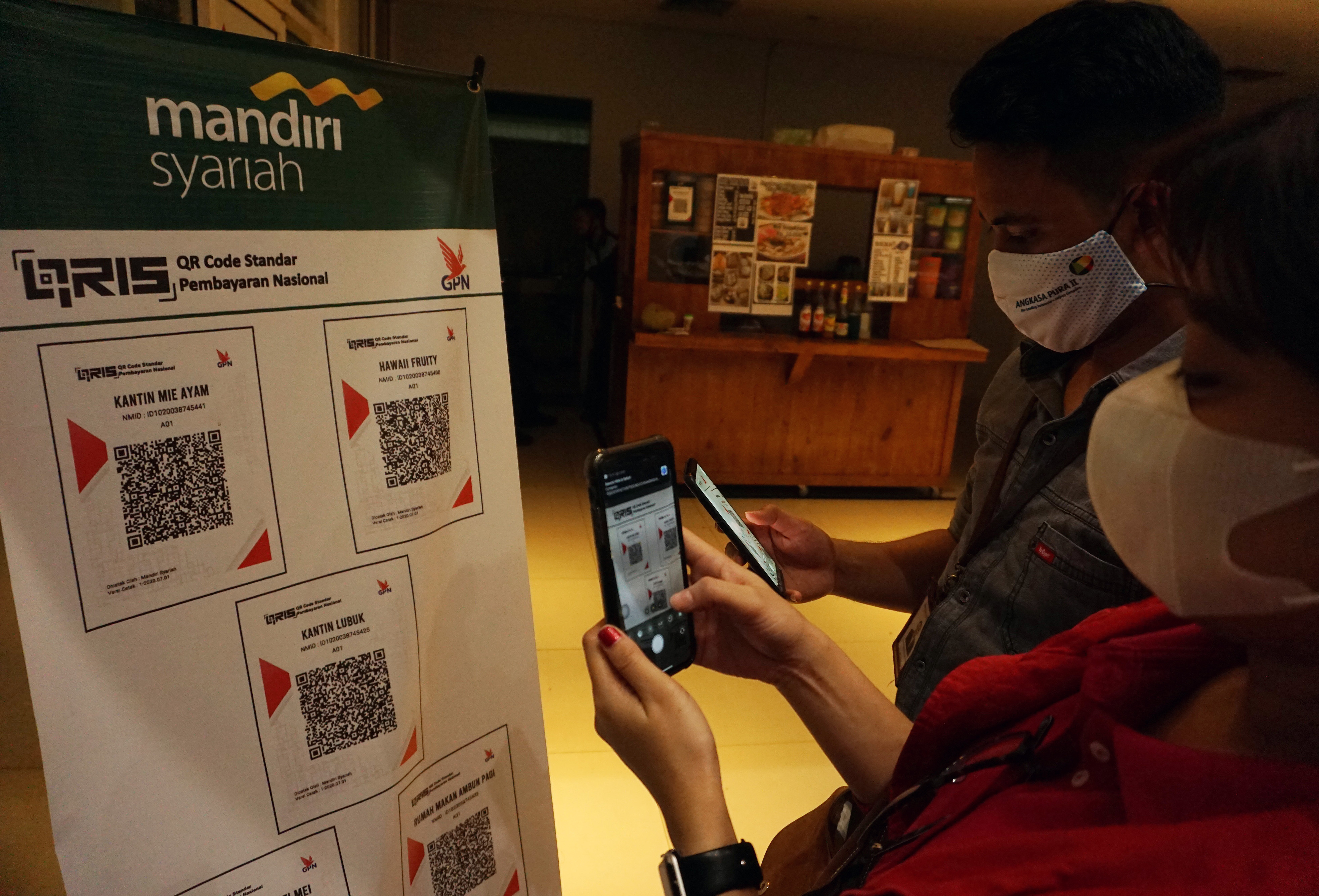 Pembeli jajanan sedang membayar menggunakan QRIS.