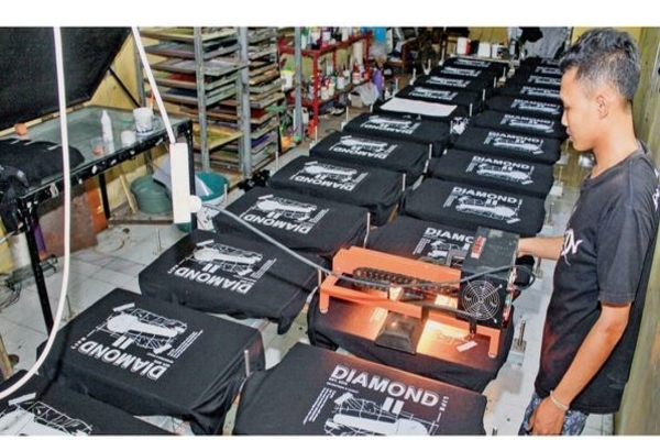 Pekerja melakukan proses pengeringan kaus yang selesai disablon di kawasan Bangsri, Sukodono, Sidoarjo, Jawa Timur, pekan lalu.