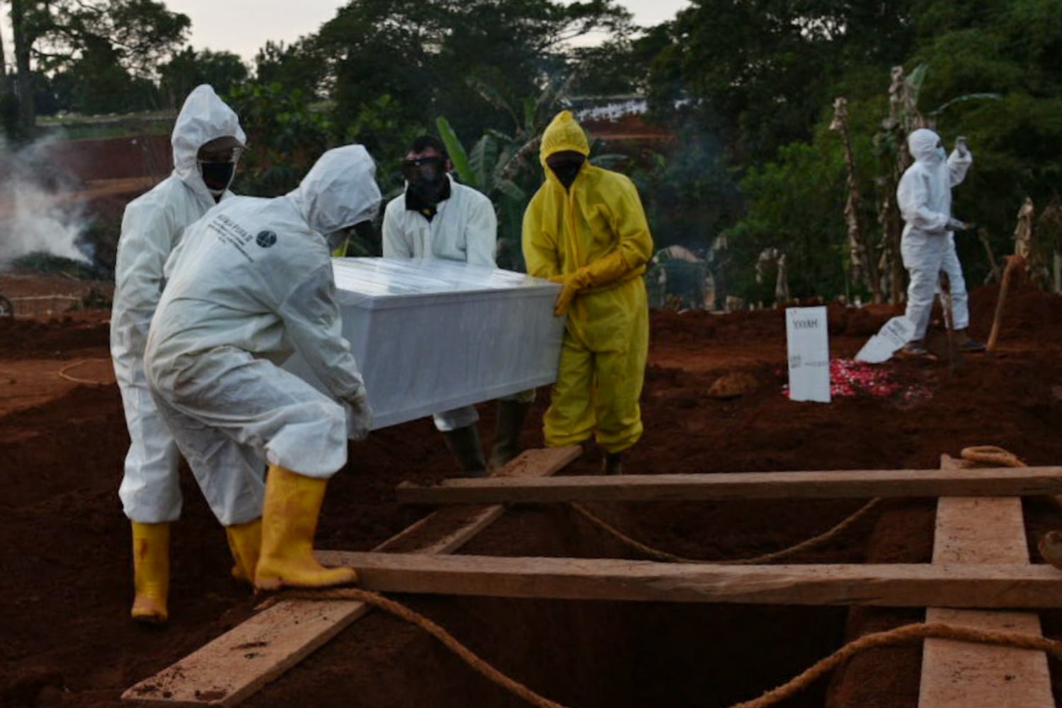 Petugas memakamkan jenazah pasien covid-19 dengan protokol ketat di TPU Pondok Rangon, Jakarta.